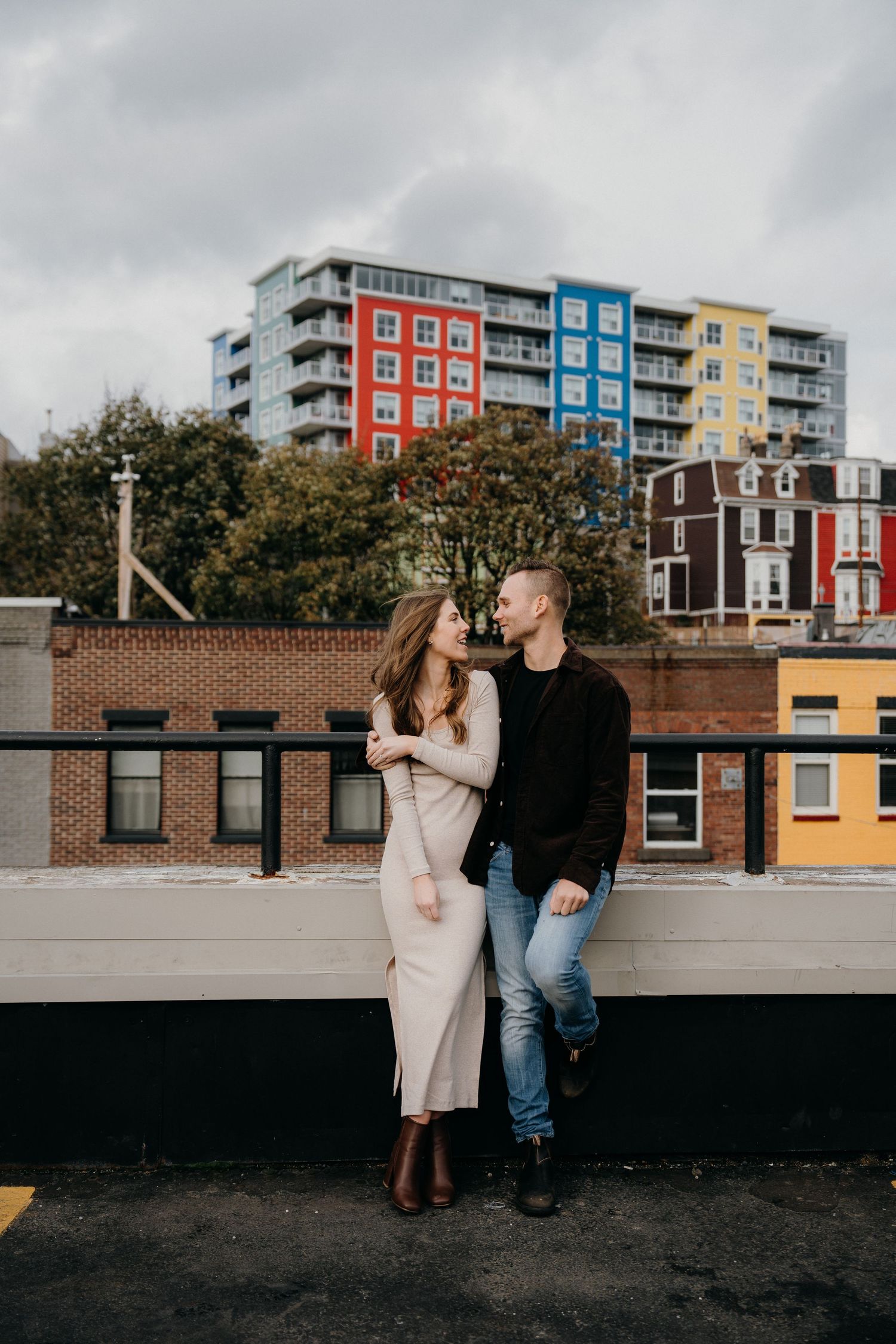 Urban rooftop photoshoot with colorful apartment buildings in background.