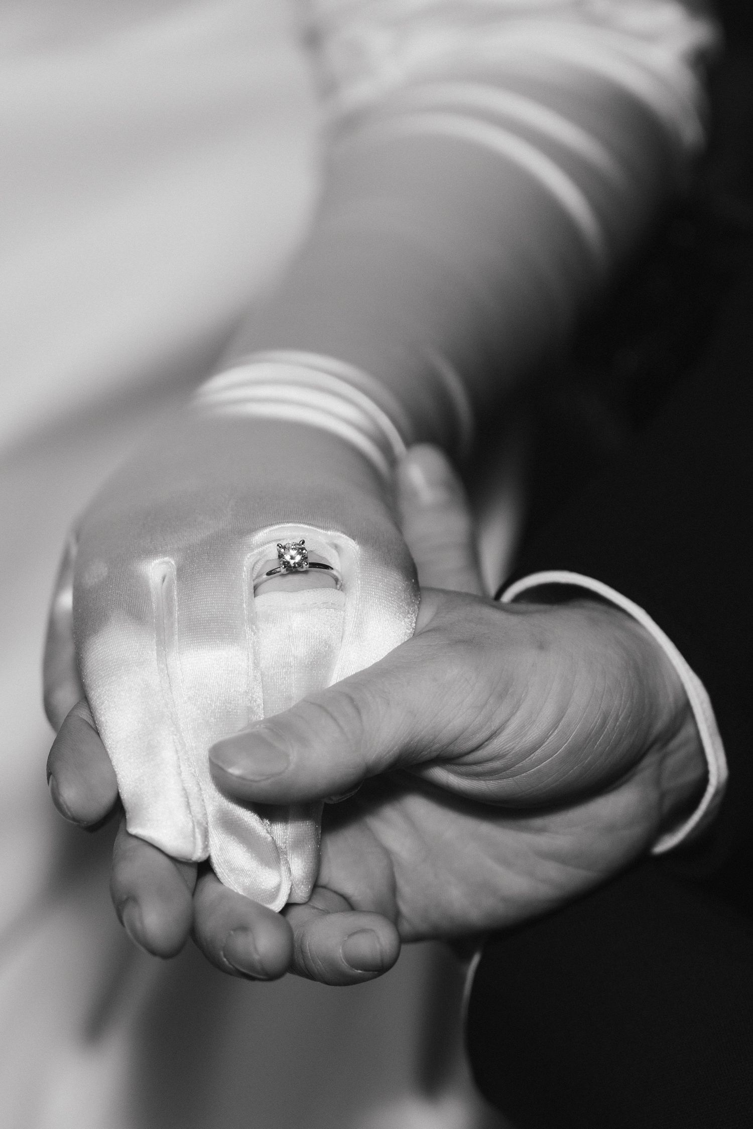 Two hands holding wedding rings are captured in a series of elegant black and white photos.