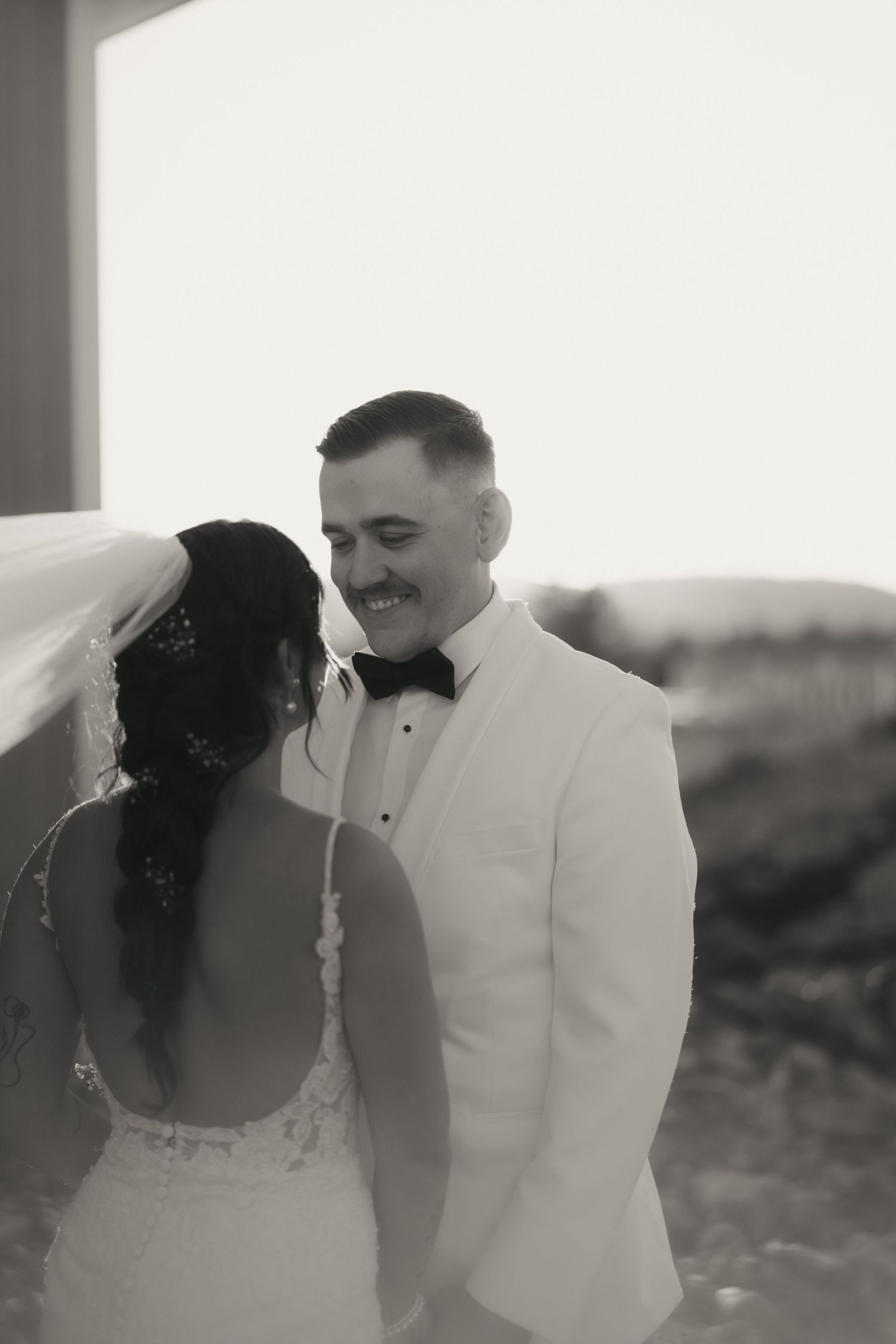 A romantic black and white wedding photo series showing tender moments between a couple in formal attire.