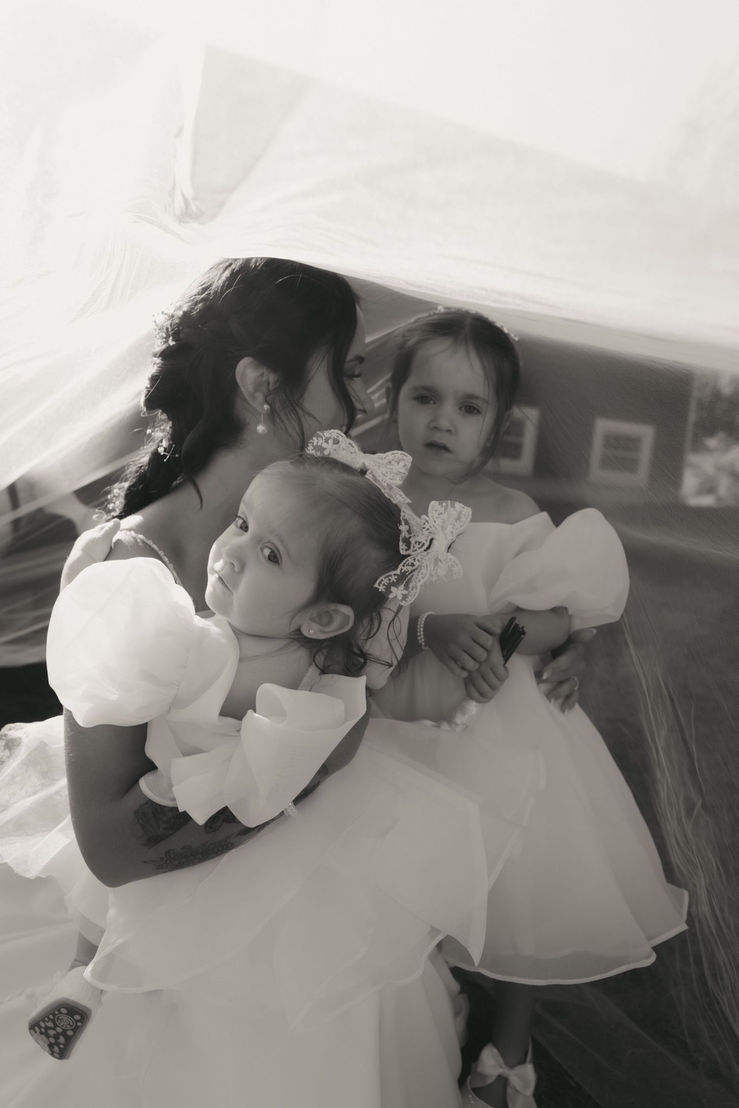A sequence of black and white photos showing two children in white dresses embracing and sharing a tender moment.