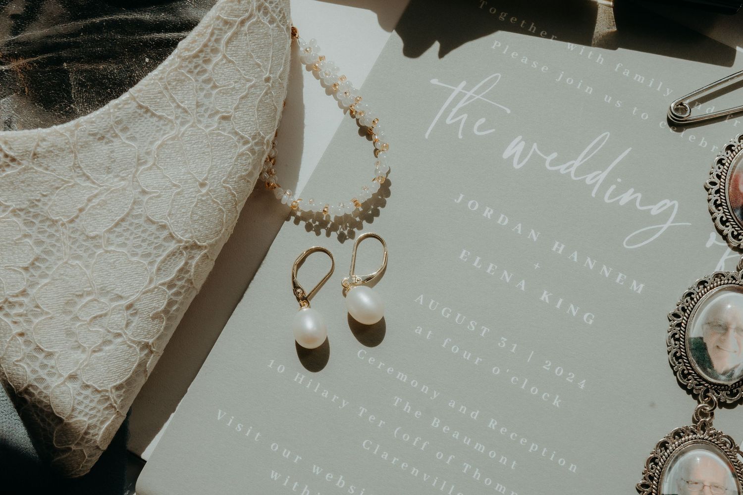 Elegant wedding invitation details with lace and jewelry on light background.