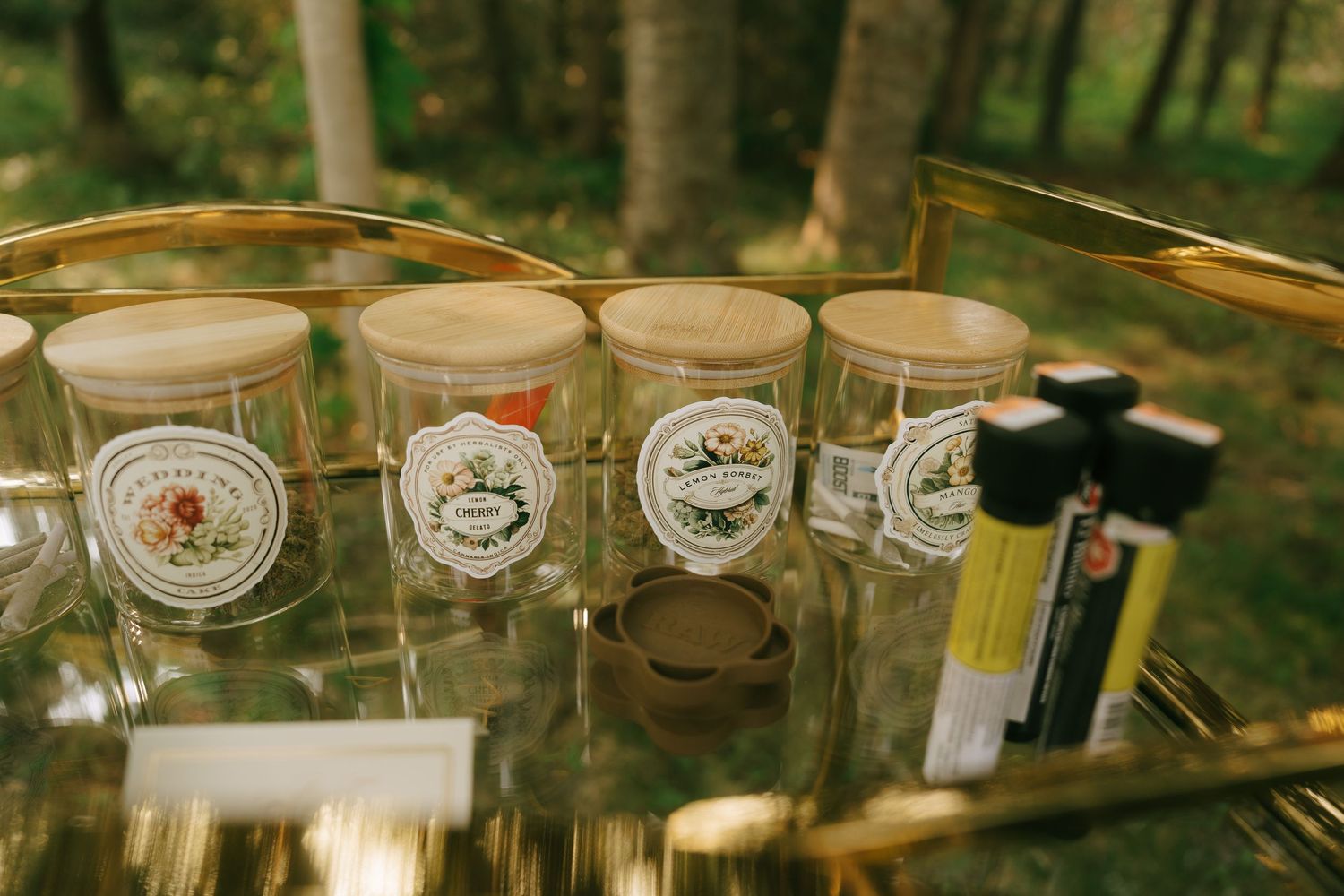 Collection of elegant teacups arranged on gold shelving in garden setting.