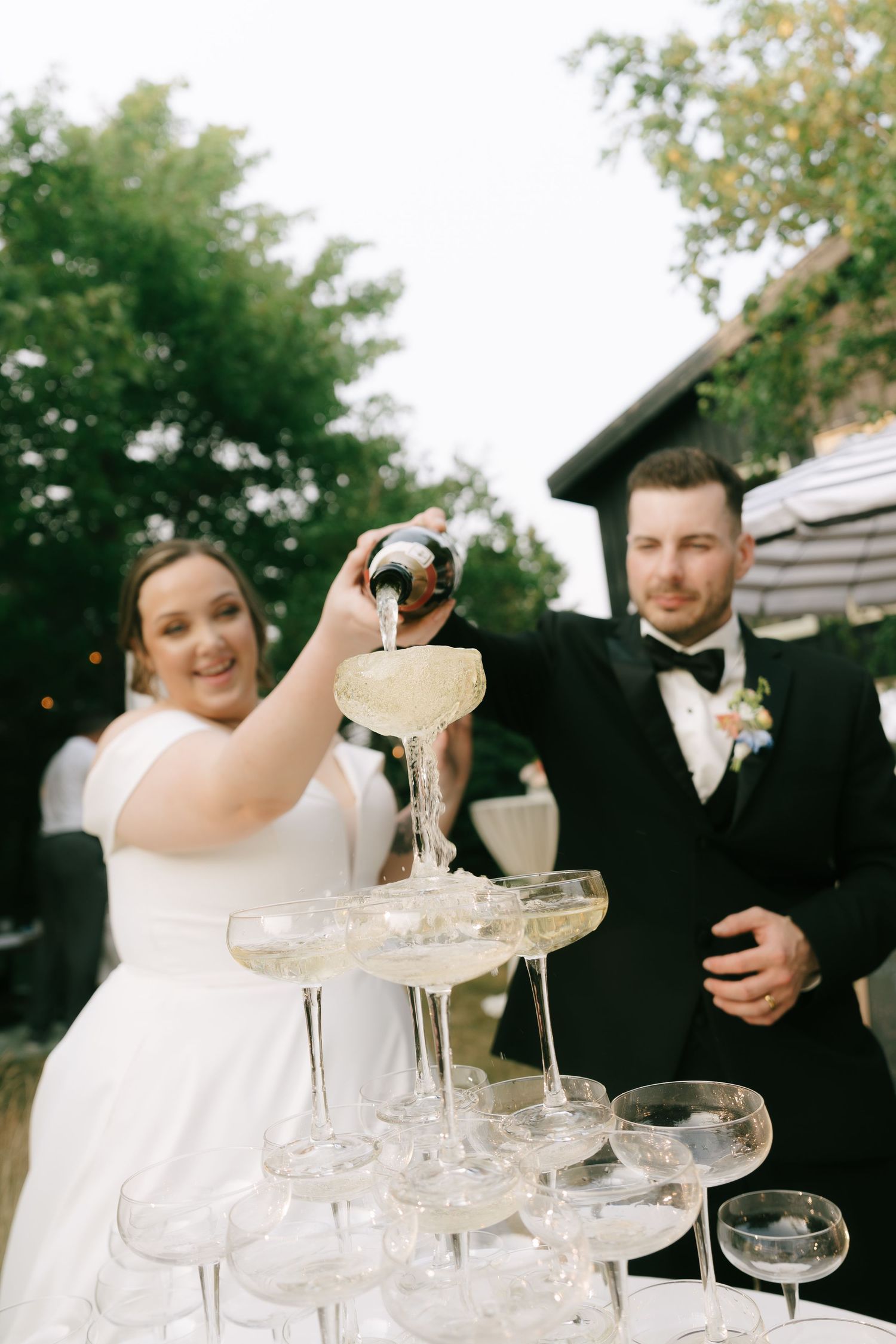 Formal wedding celebration features champagne being poured into a multi-tiered glass tower.