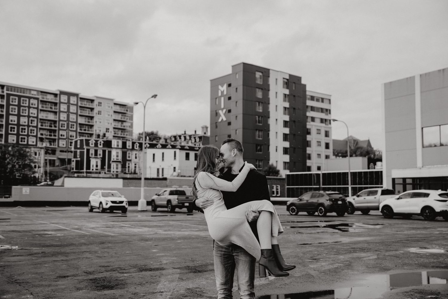 Partners executing a dramatic dance dip in a deserted parking lot with city skyline visible.