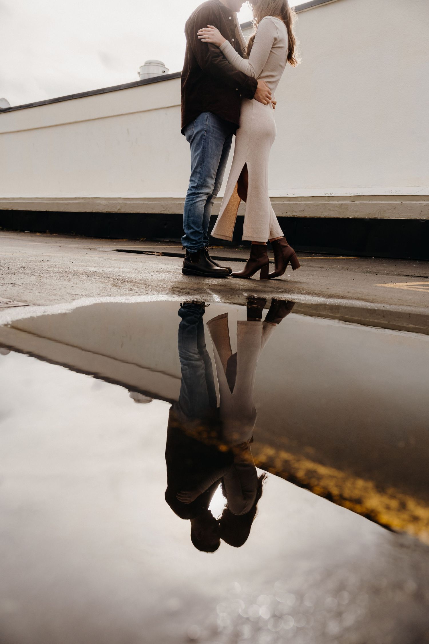 Creative composition showing a couple's reflection in rainwater against modern architecture.