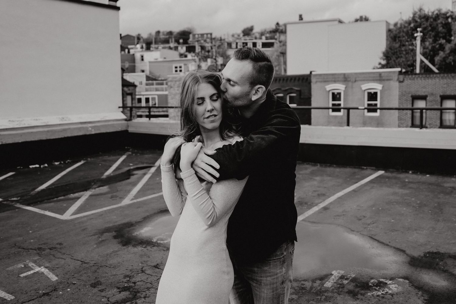 Intimate monochrome portrait of couple standing close together on rooftop parking area.