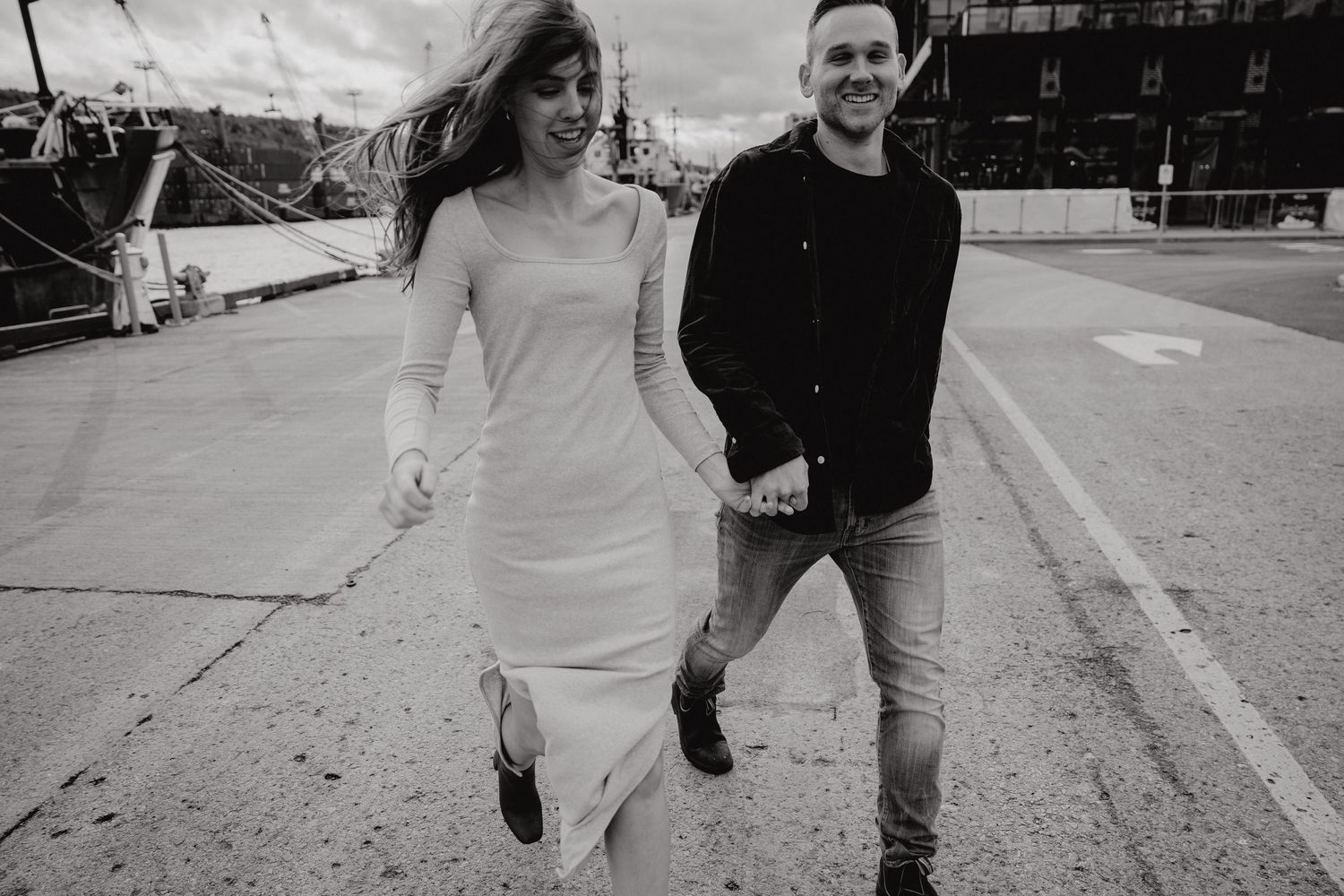 A joyful black and white photo of a couple running together outdoors.