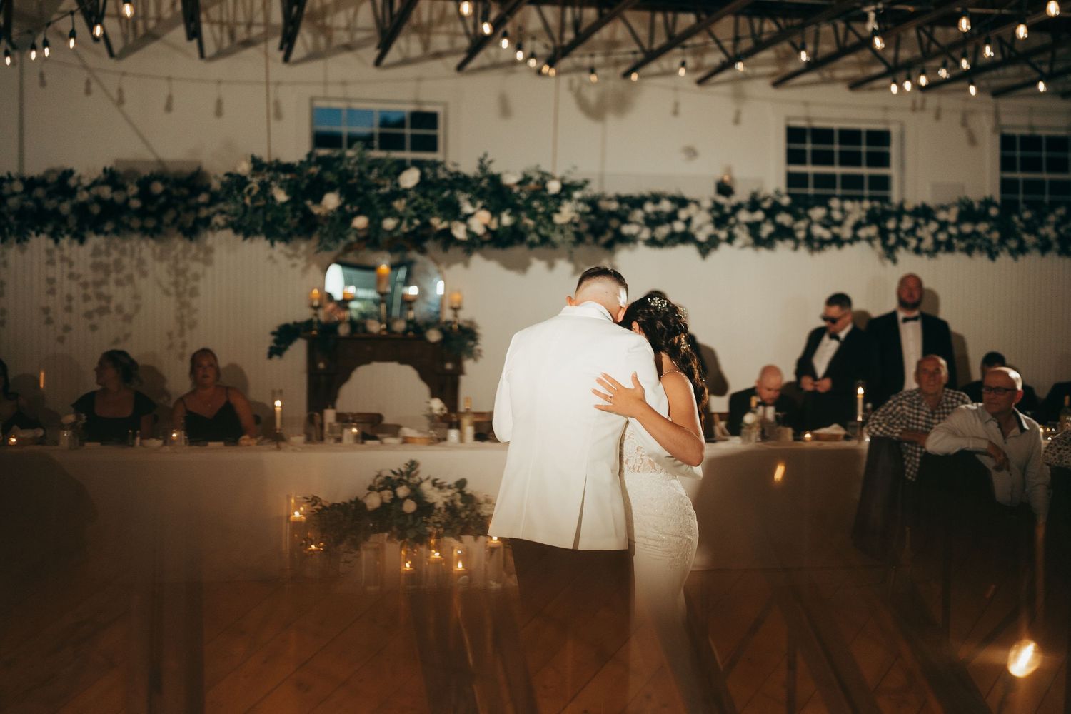 A romantic wedding reception venue decorated with twinkling string lights and soft ambient lighting creates a magical atmosphere.