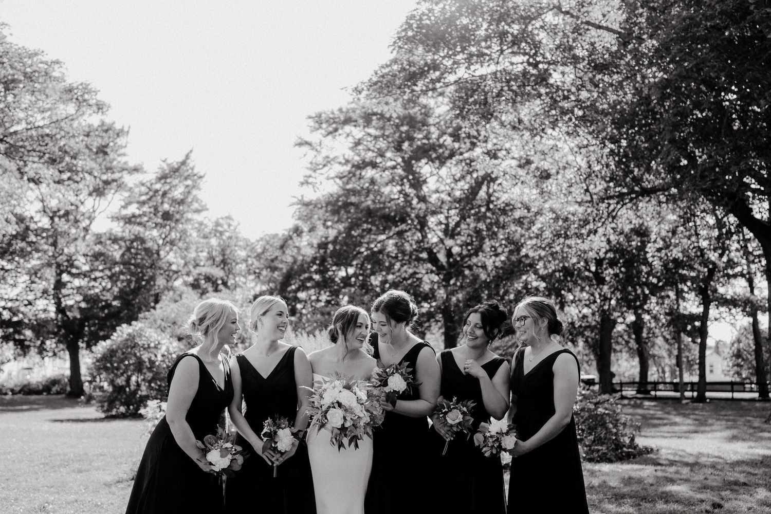 Wedding party posed together under blooming spring trees in natural outdoor setting.