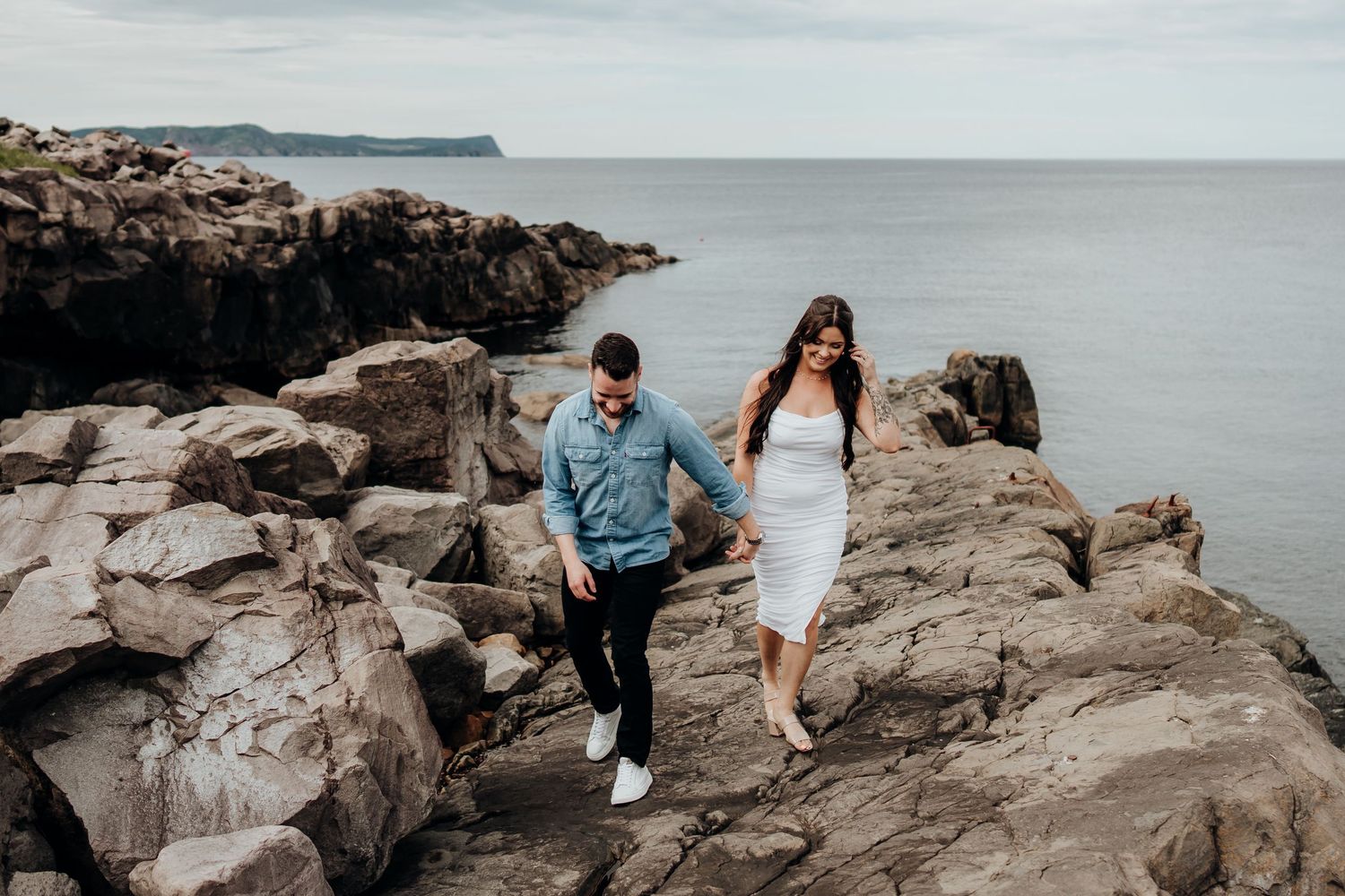 Couple adventuring together on dramatic rocky oceanfront cliffs.