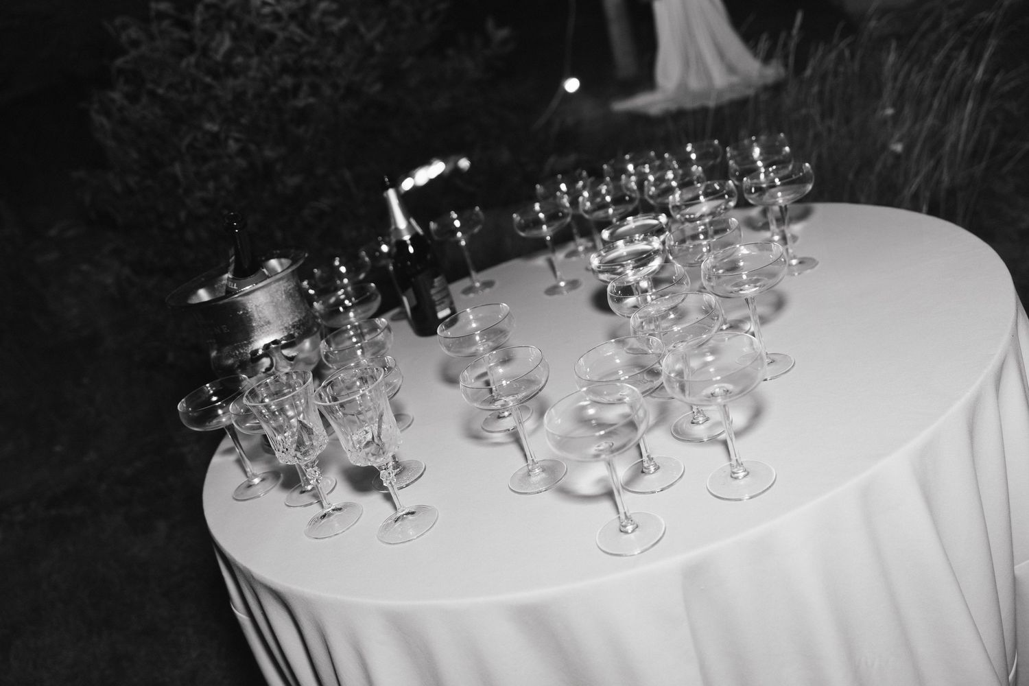 A series of elegant champagne glasses arranged on a white tablecloth at a formal event.