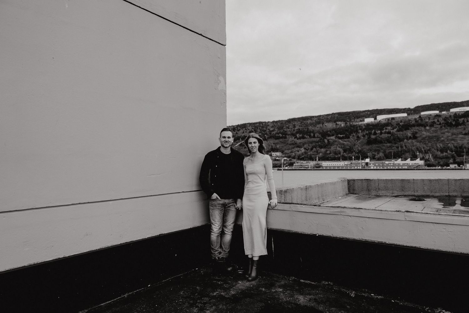 Couple photographed against coastal scenery and modern architecture.