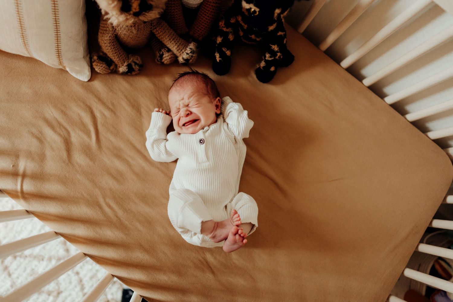 Gentle family interactions captured on soft neutral bedding in warm natural light.