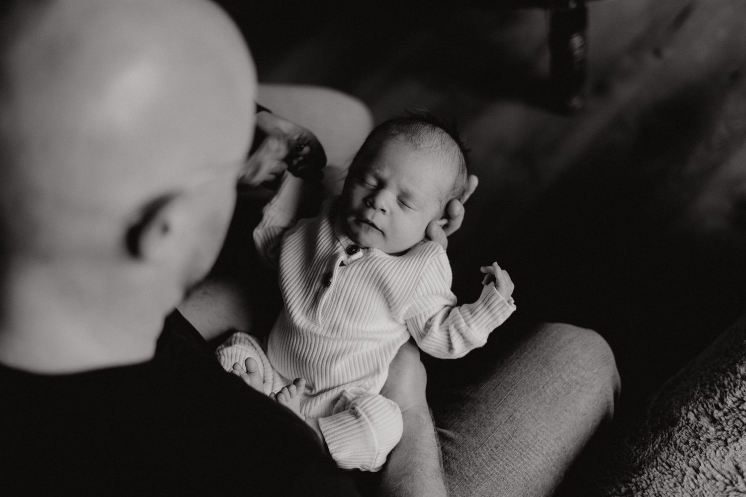 Dramatic black and white portrait showing tender family interactions in soft lighting.