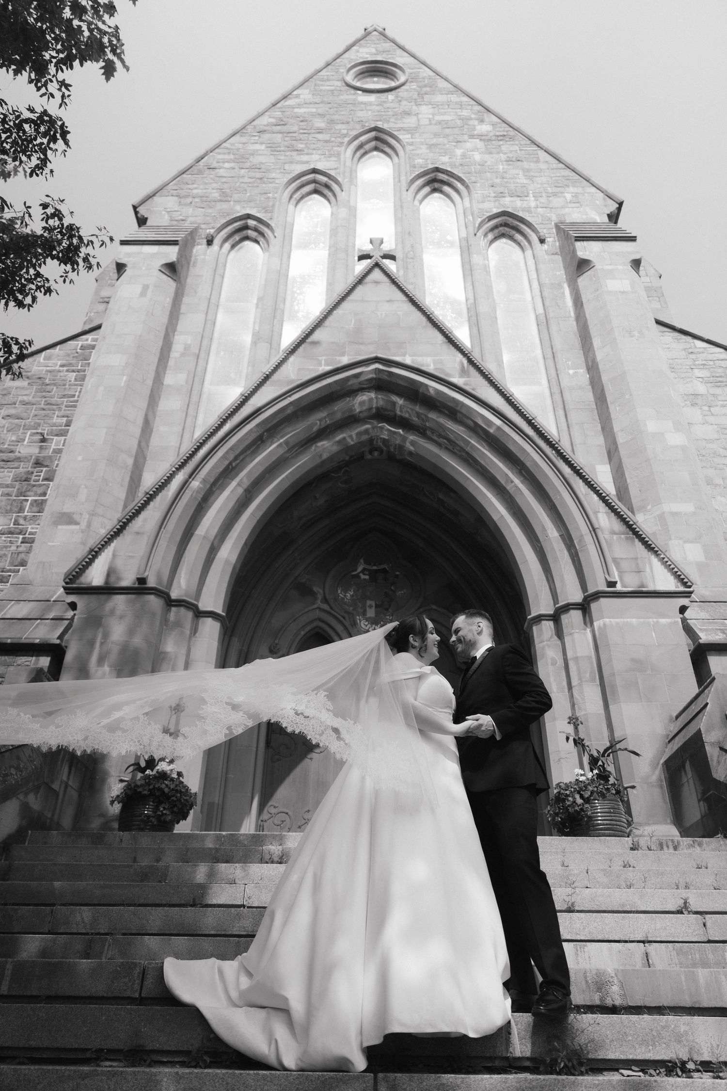 A romantic wedding moment photographed on the steps of a Gothic stone church.