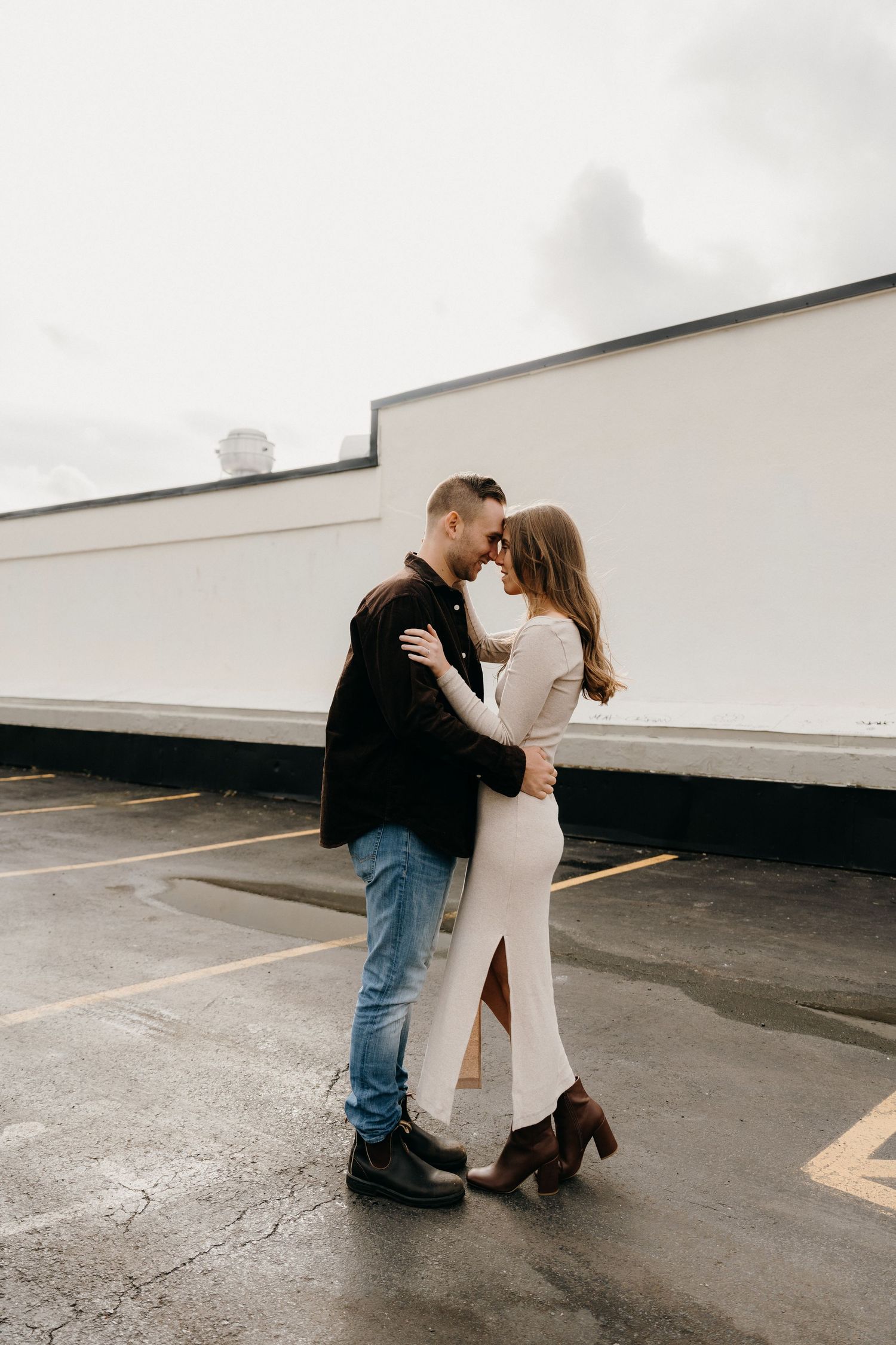 Couple in casual attire sharing an intimate moment in a parking lot.