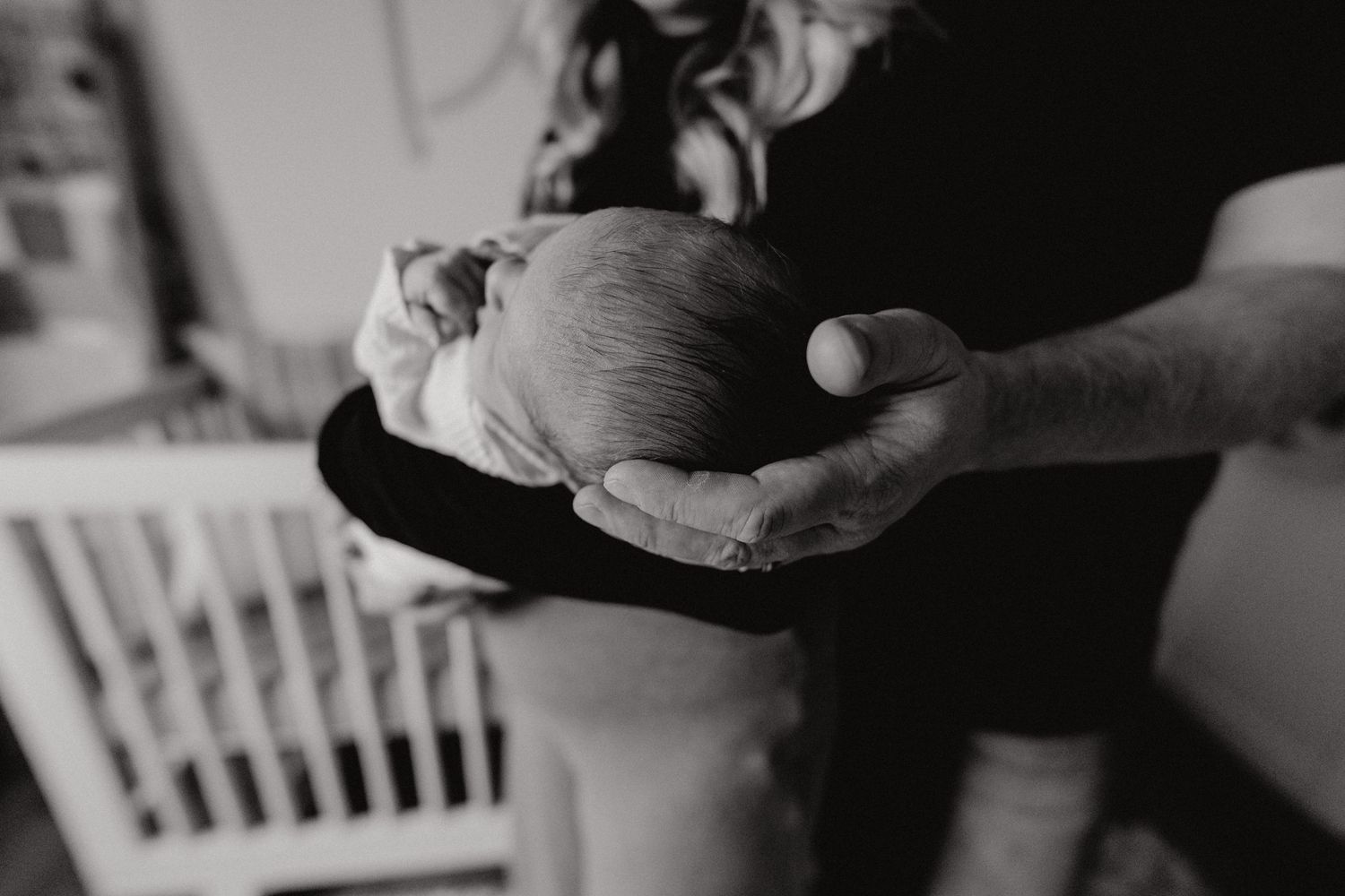 Close-up black and white photograph capturing tender moments with a newborn.