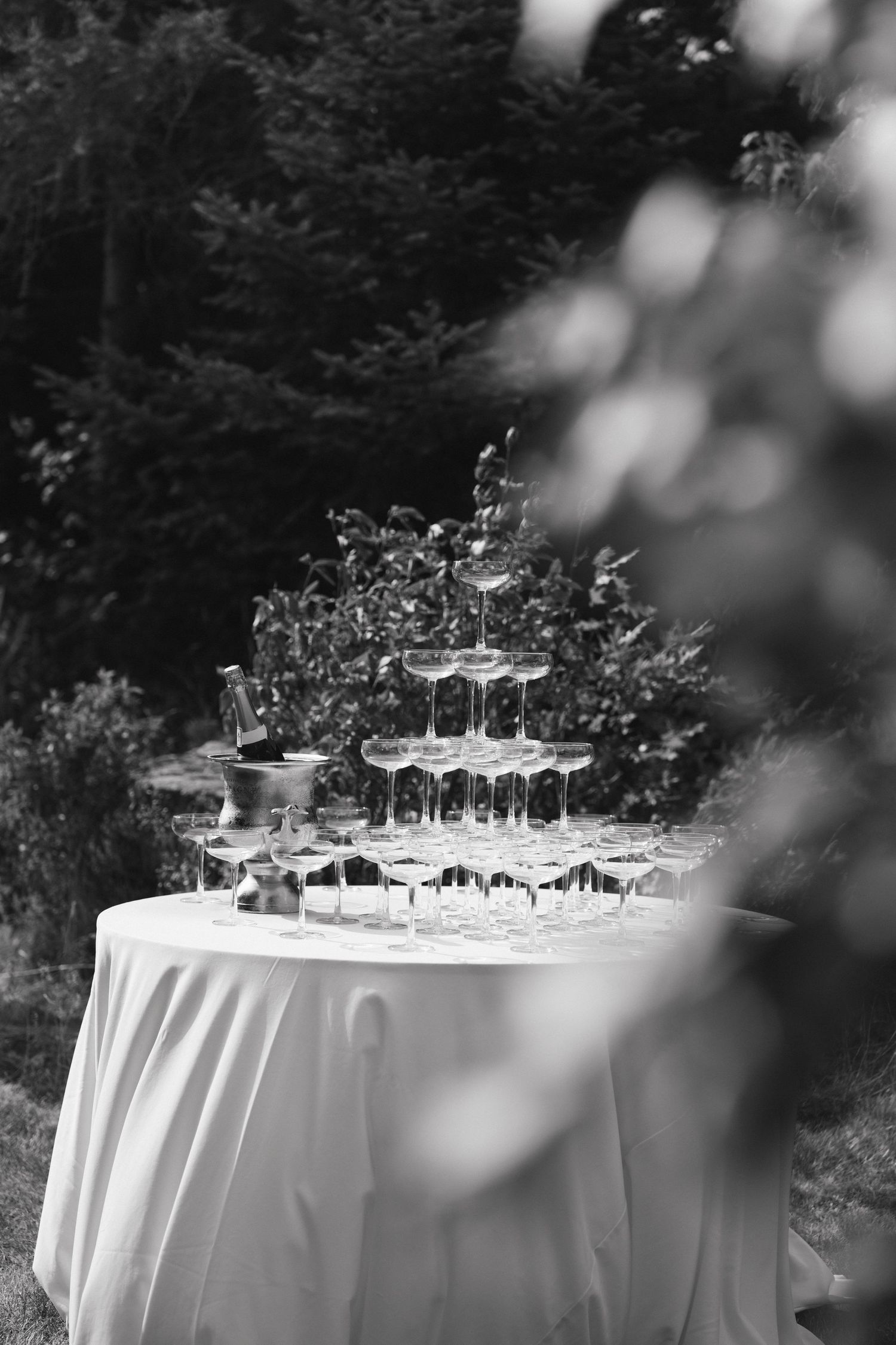 Elegant table setting with glassware and white linens for outdoor wedding reception.
