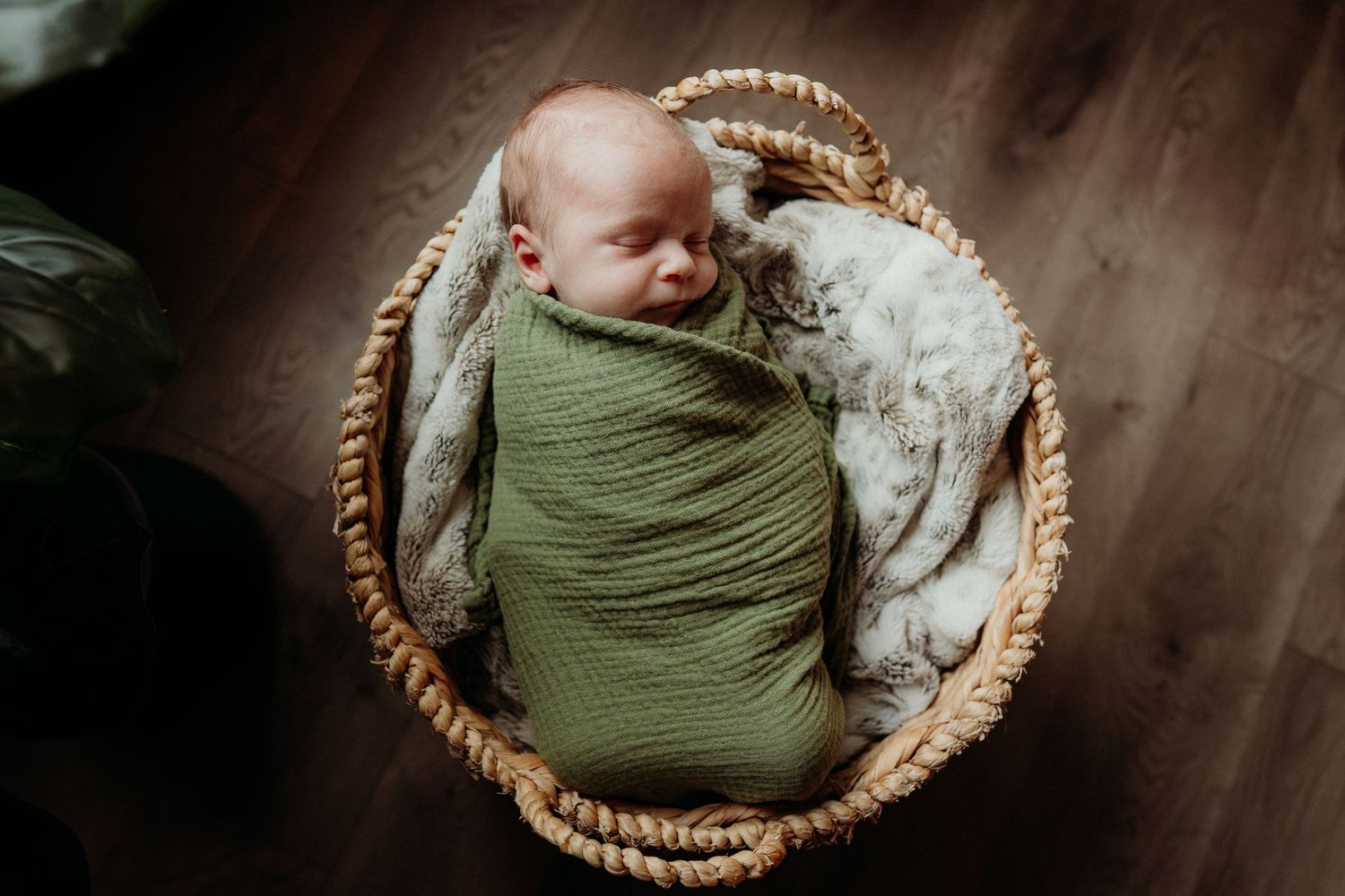 Artistic portrait of sleeping newborn in round basket with soft lighting.