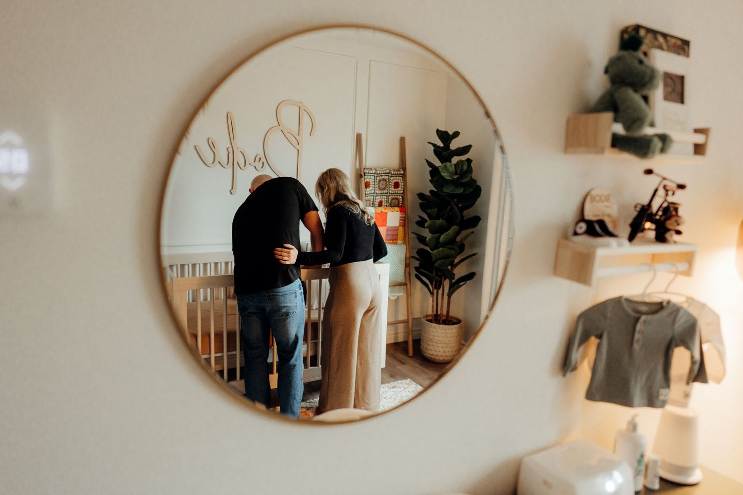 Modern circular mirror mounted on wall with soft lighting and decor elements.
