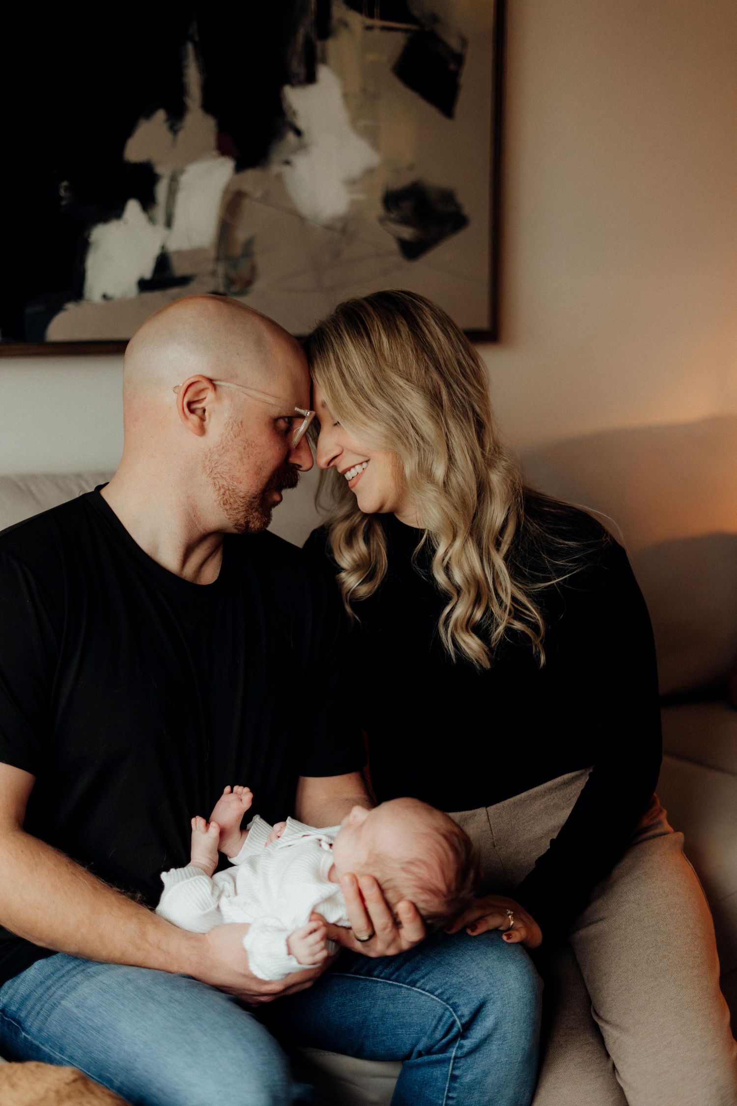 Black and white portrait capturing intimate family moment together on sofa with newborn.