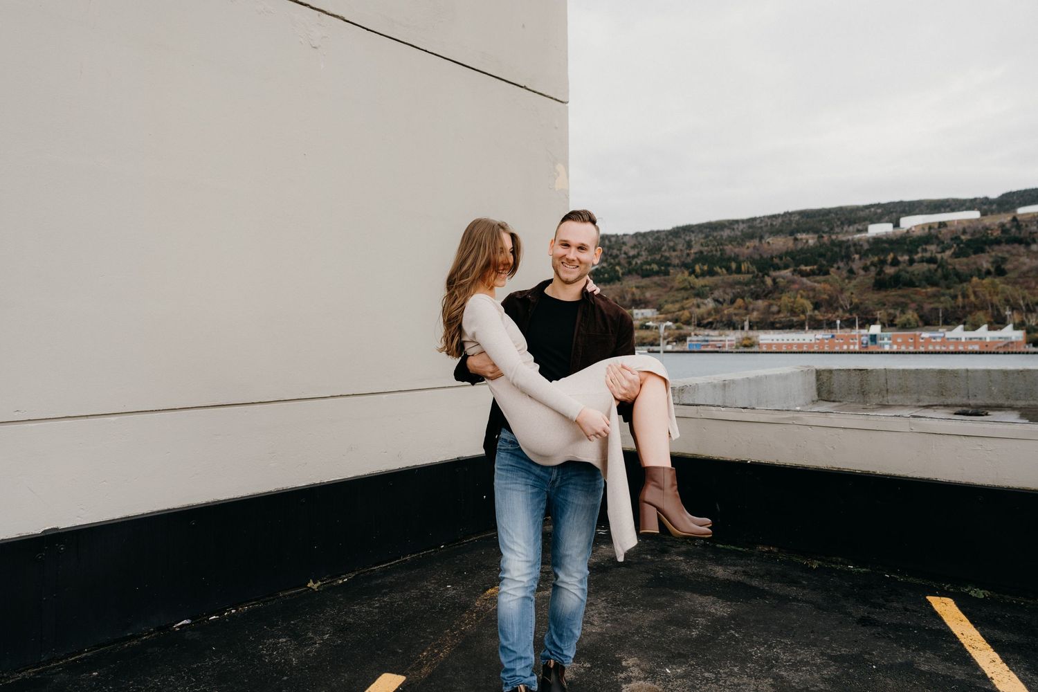 A romantic photoshoot on a concrete rooftop with scenic coastal backdrop.