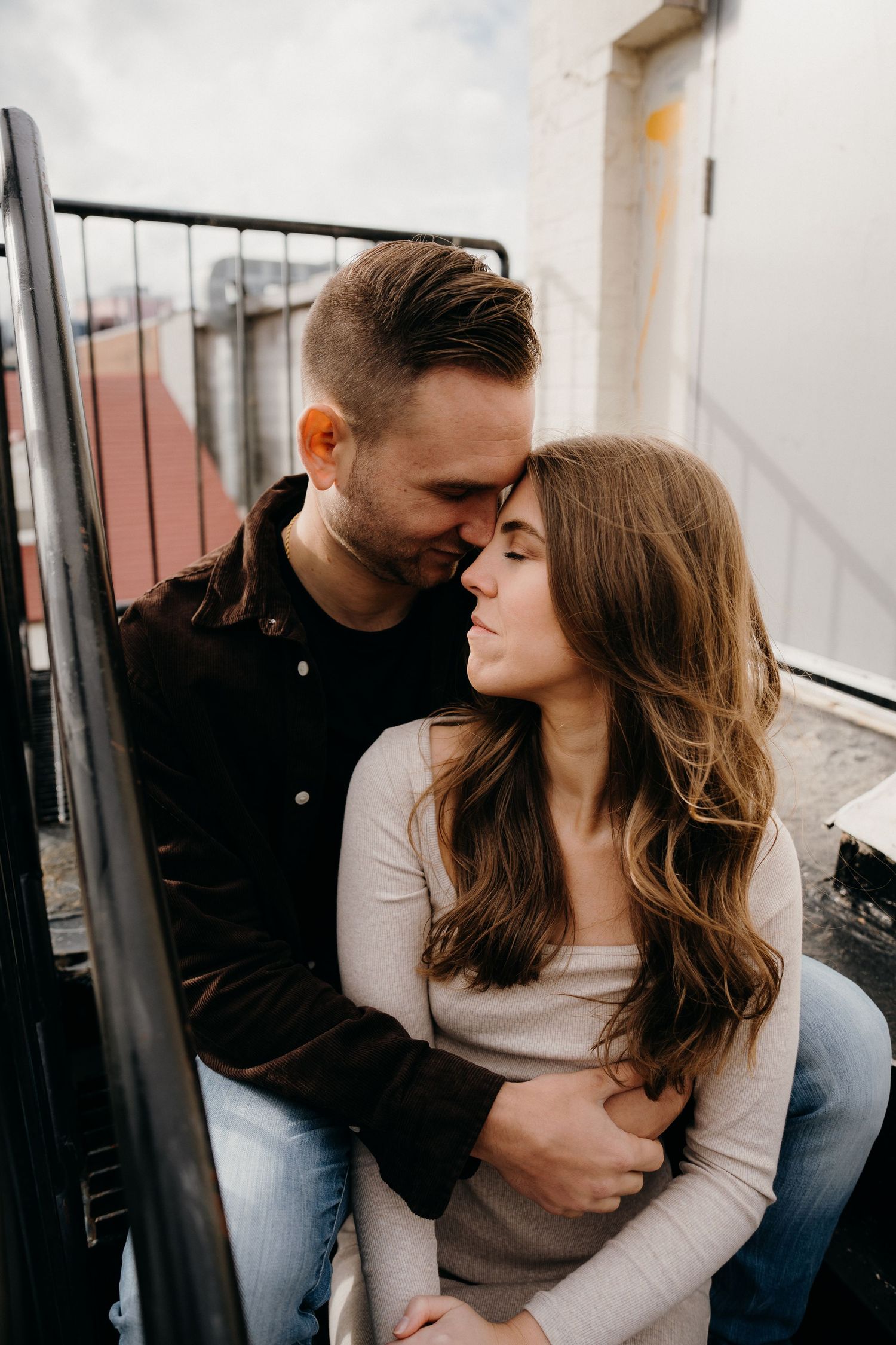 Couple in casual attire sharing affectionate moments during outdoor photo session.