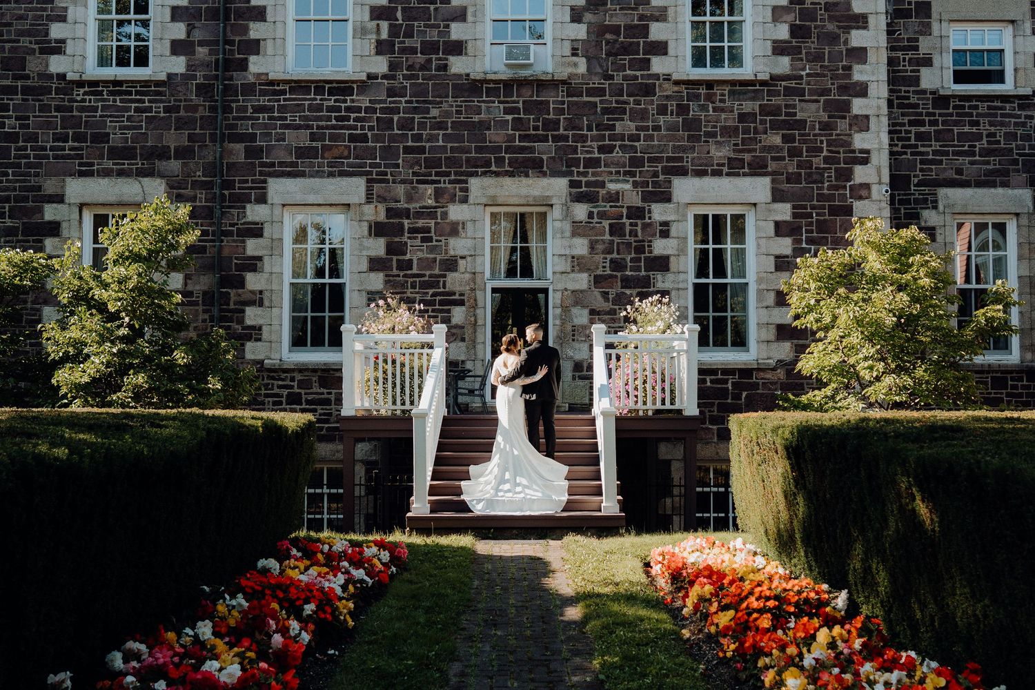 Historic stone building with white windows serves as elegant wedding venue backdrop.