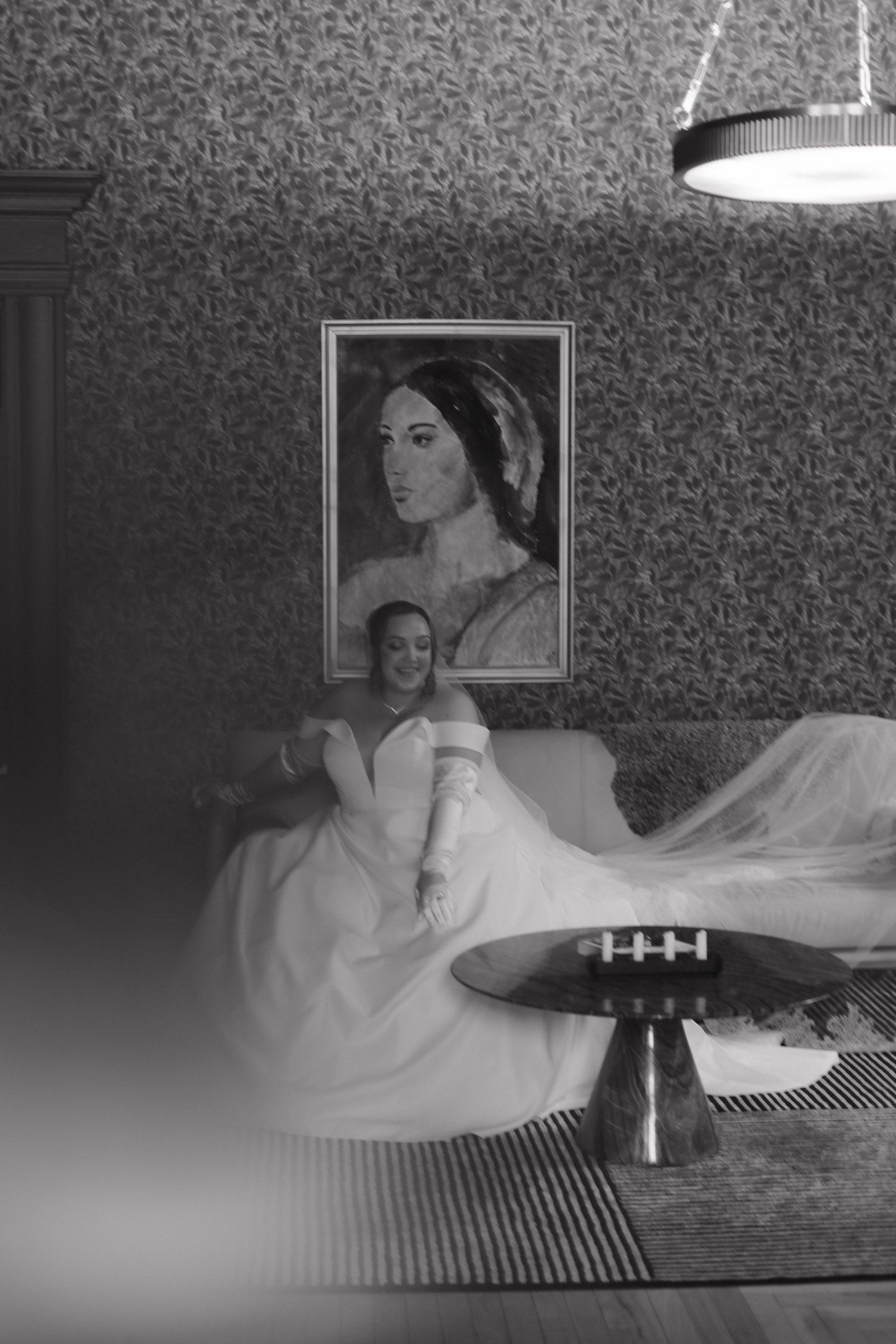 Black and white photograph of a bridal scene with vintage wallpaper and dramatic lighting.
