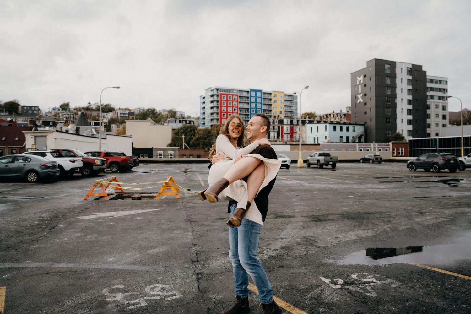 Dramatic dance pose performed in an industrial cityscape setting under cloudy skies.