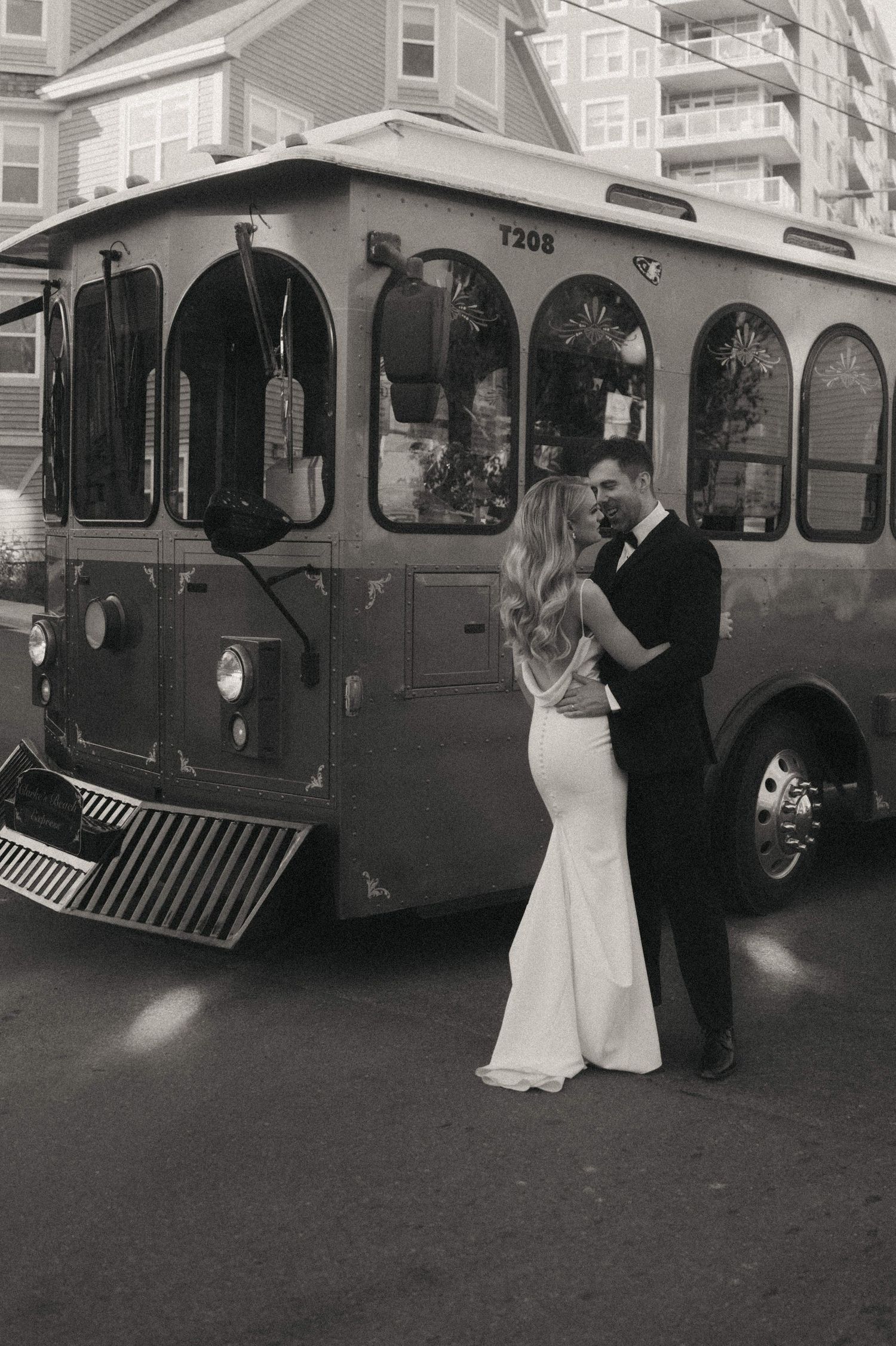 Wedding couple dancing in front of vintage trolley car on city street.