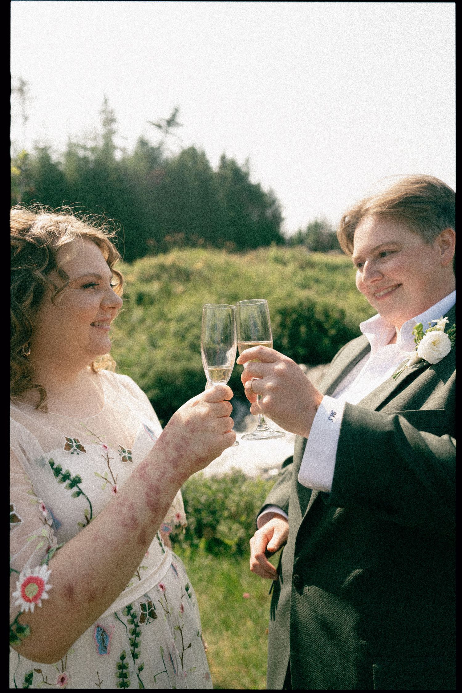 People in formal attire raise champagne glasses for a celebratory toast outdoors.