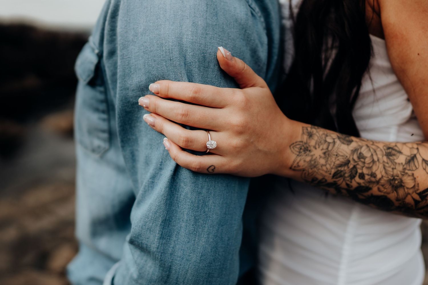 Detail shot focusing on intimate embrace and tattooed arms.