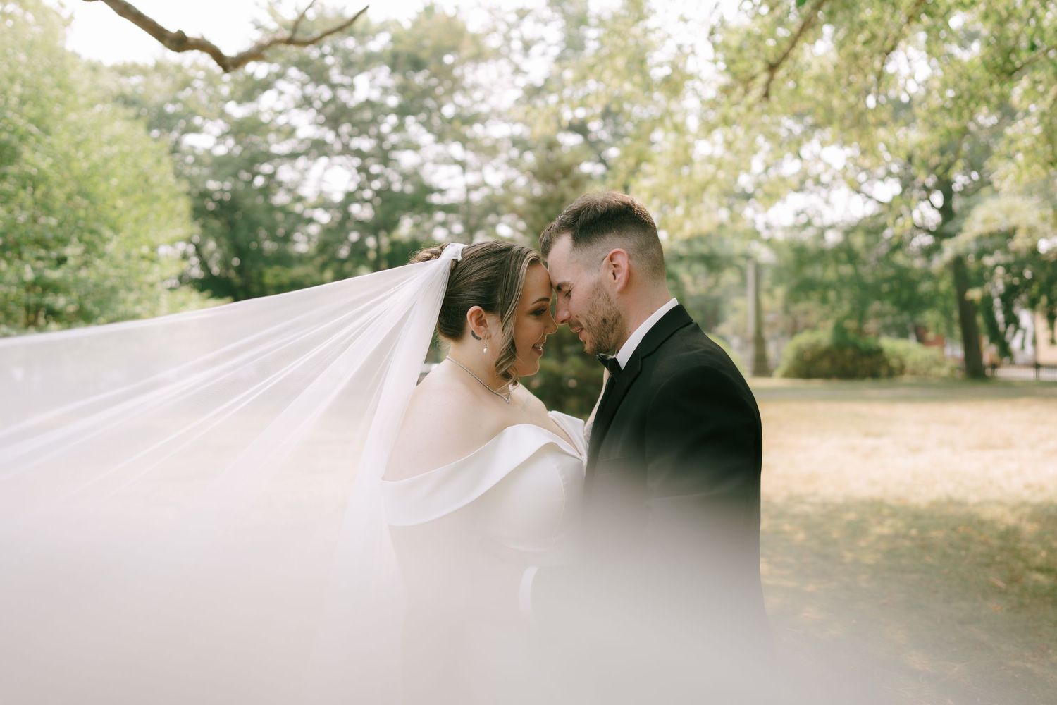 Romantic outdoor wedding photos captured with soft natural lighting and white veil details.
