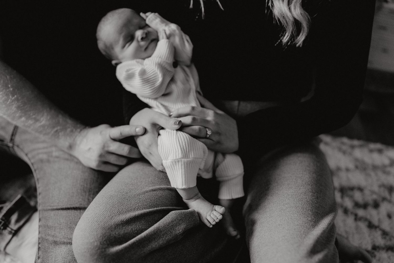 Artistic black and white portrait of an infant being gently held.
