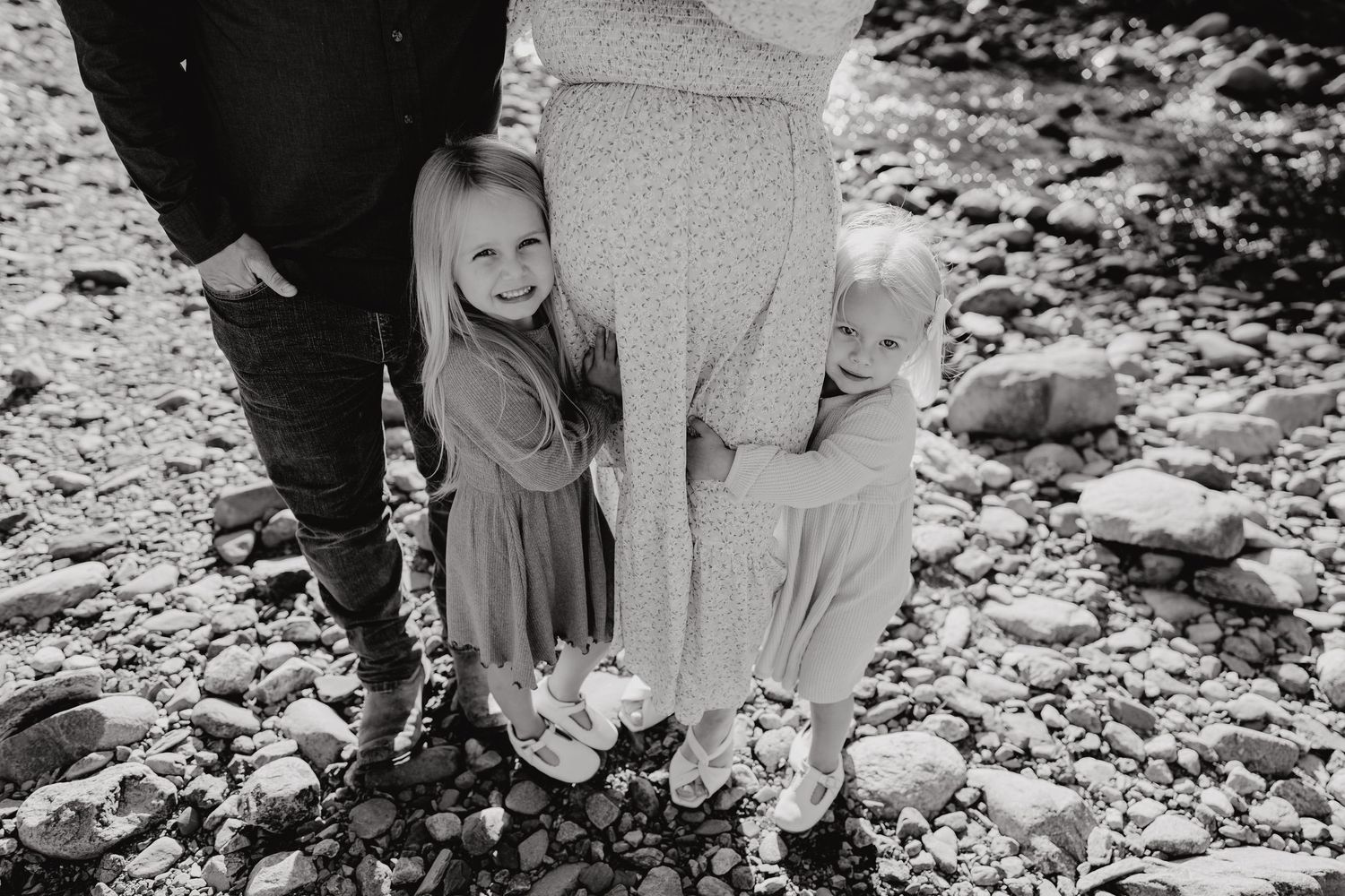 Black and white photo of legs and feet gathered on a rocky beach.