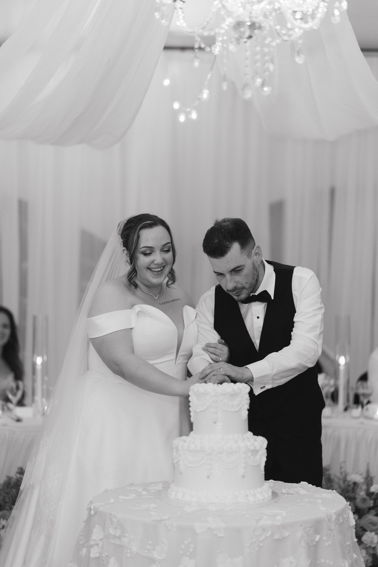 A couple cuts their elegant white wedding cake together during their reception.