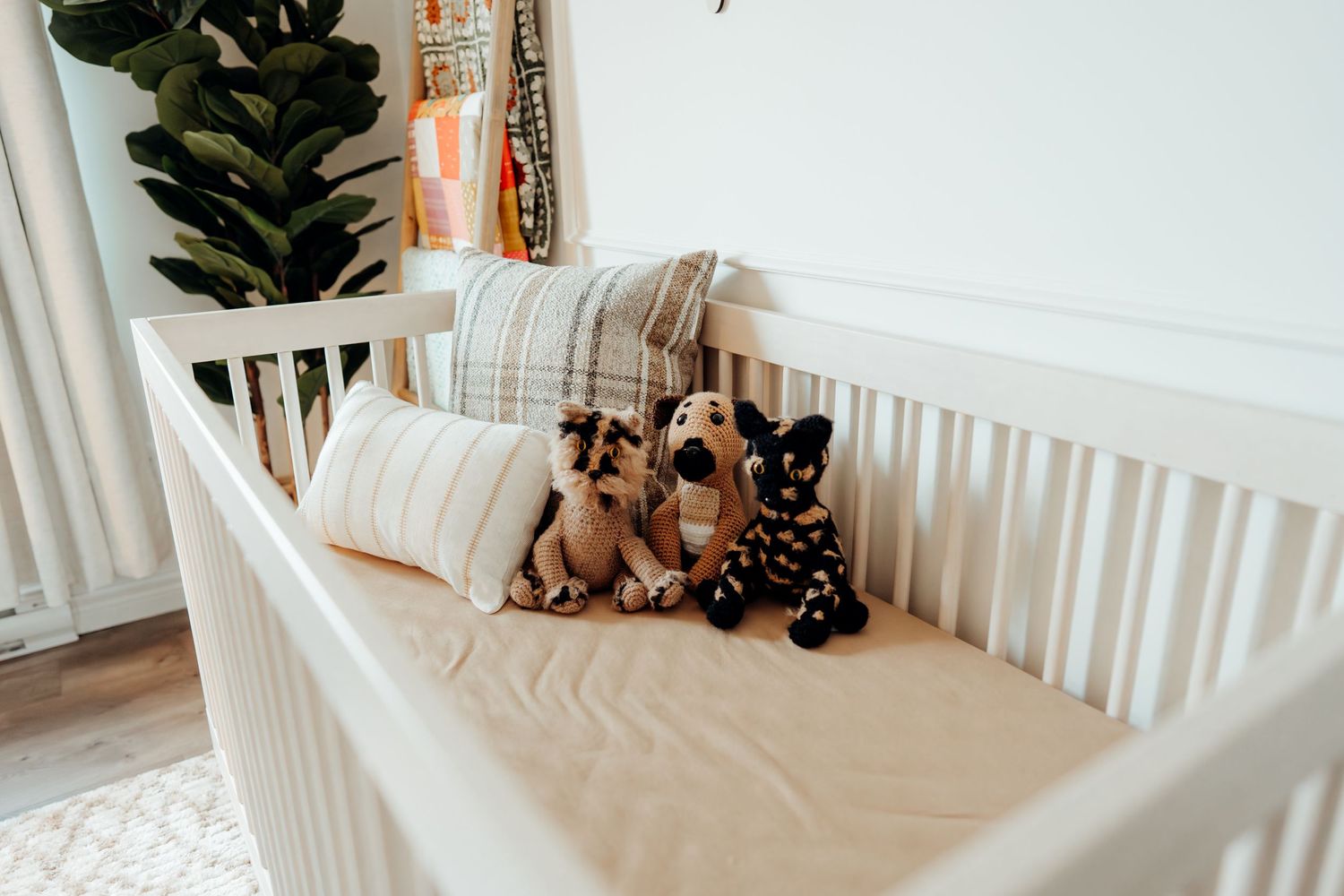 Modern nursery featuring a white crib with stuffed animals and minimalist wall decor.