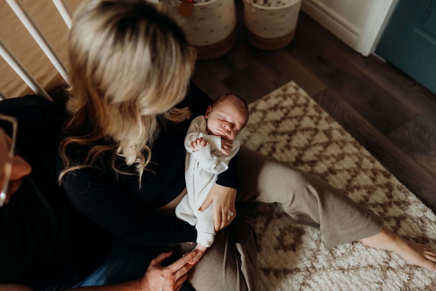 Close-up view of an infant being cradled on a decorative carpet in natural light.