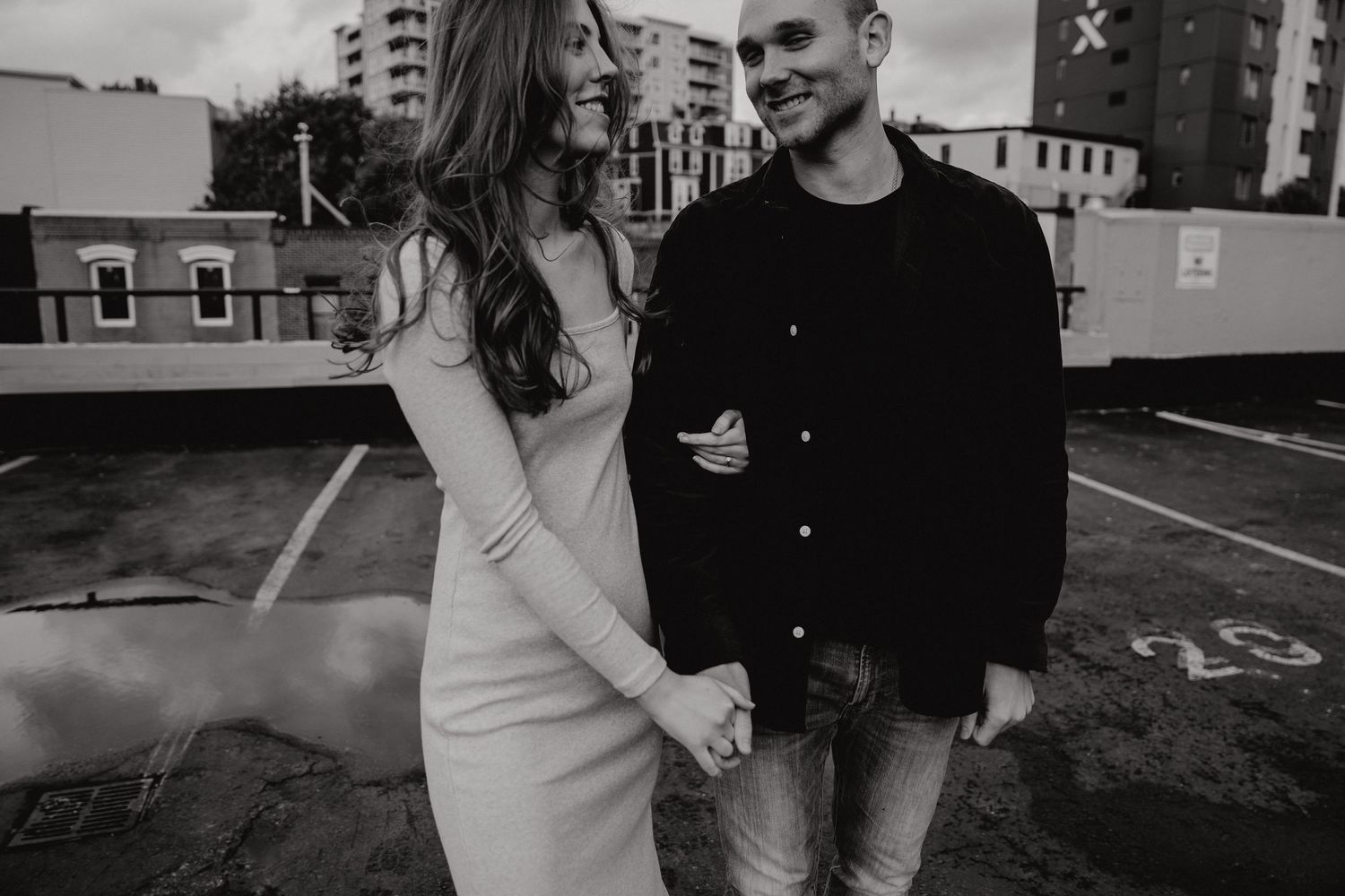 A couple laughs together during a casual photoshoot in an urban setting.