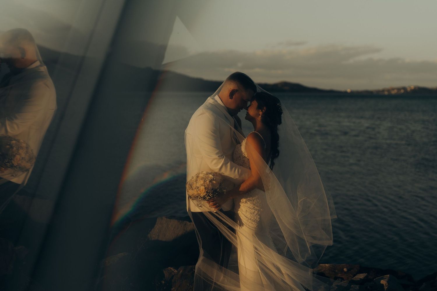 A romantic couple embraces during sunset by the ocean in a series of intimate wedding photos.