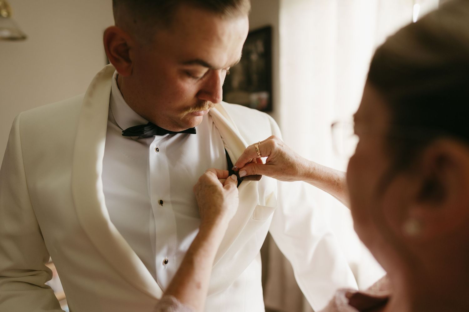 A series of intimate wedding preparation moments showing details of formal attire and quiet interactions in natural light.