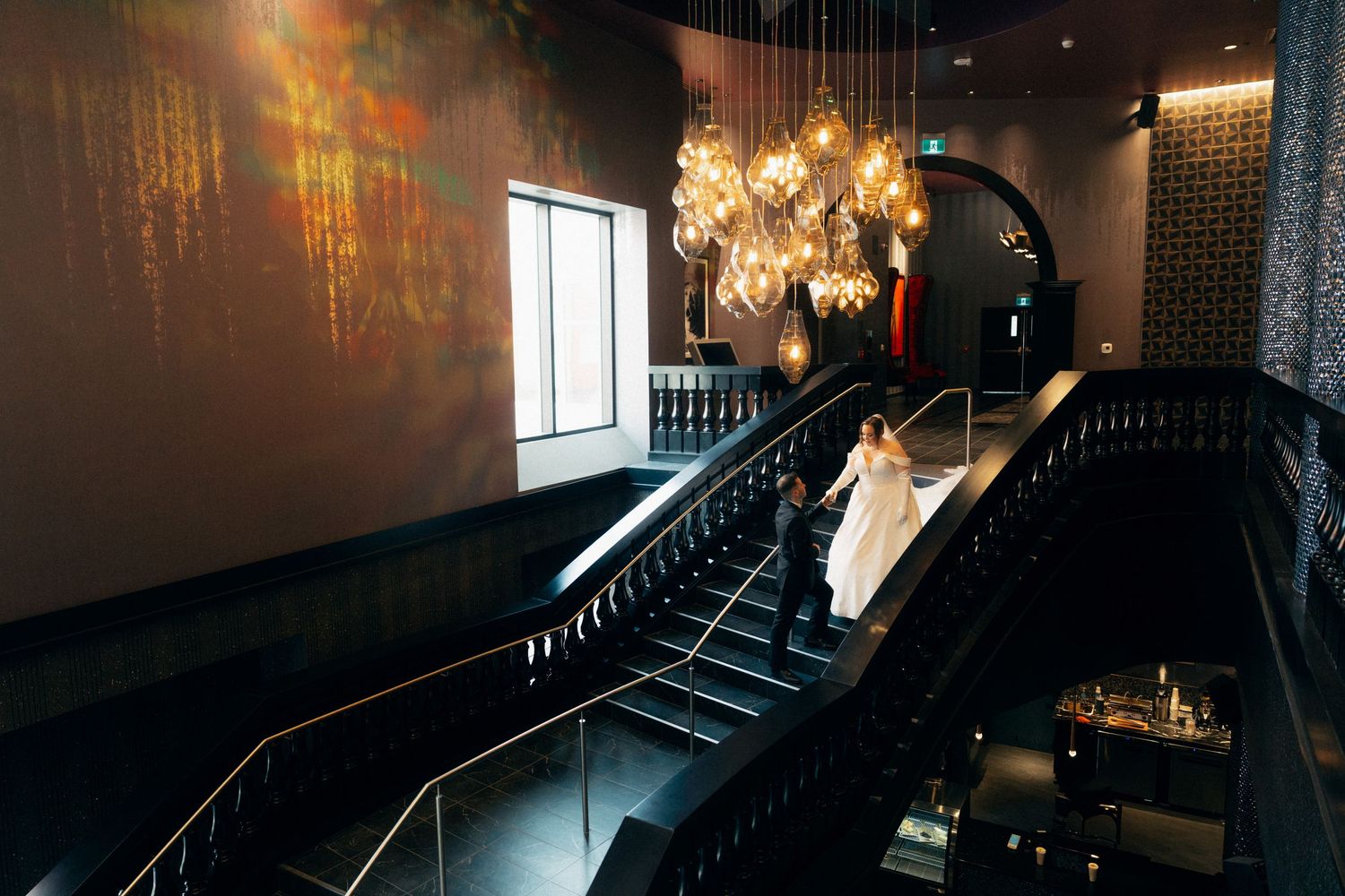 Modern venue interior features a curved staircase with contemporary lighting fixtures creating romantic ambiance.