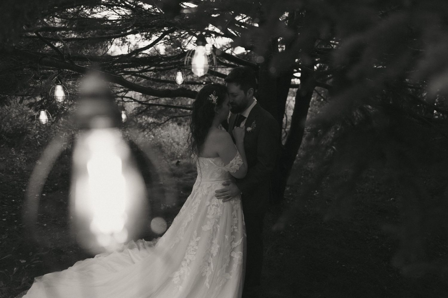 A romantic wedding couple walks through a misty forest path with elegant formal attire and natural lighting.