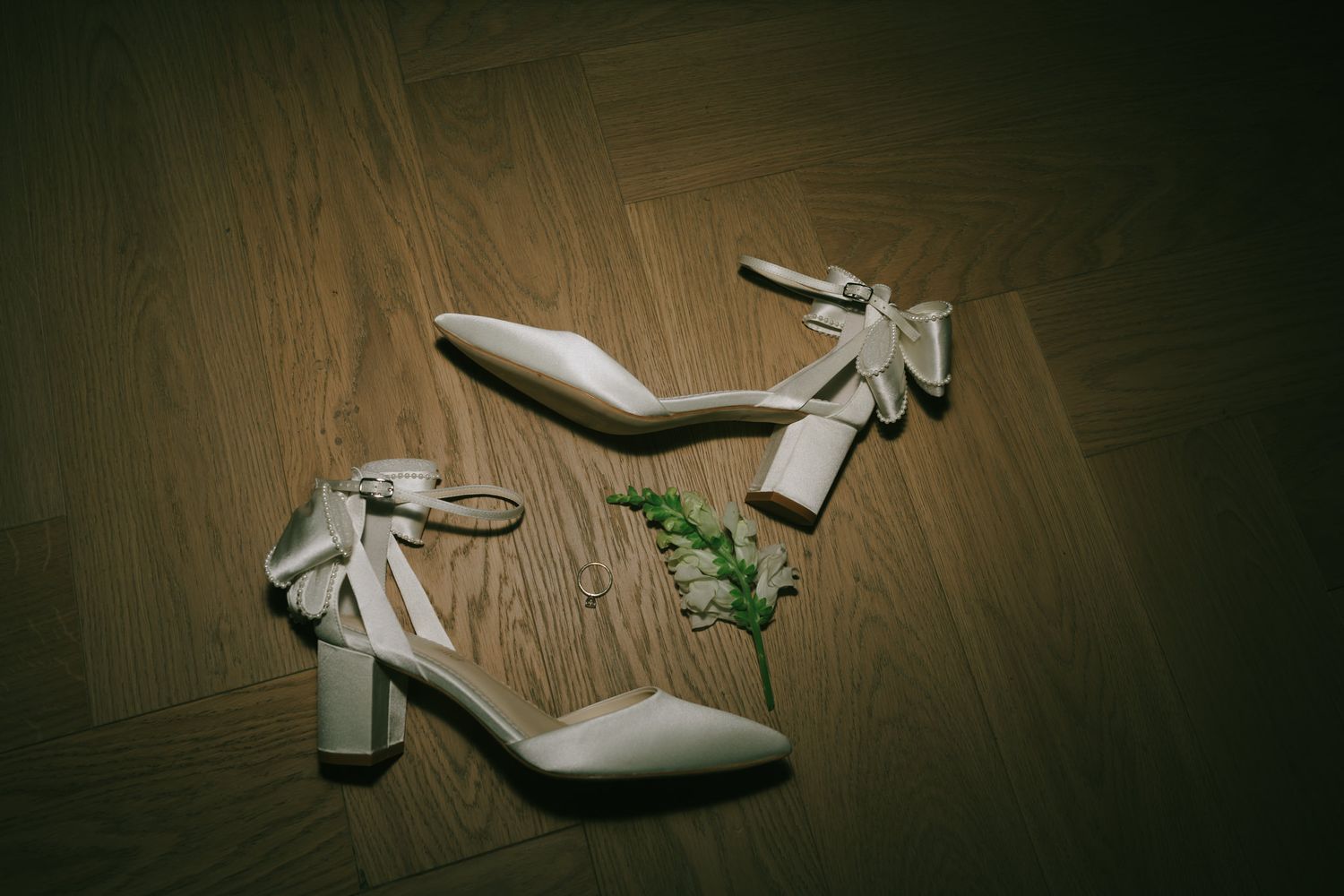 Wedding shoes positioned artistically on dark hardwood flooring.