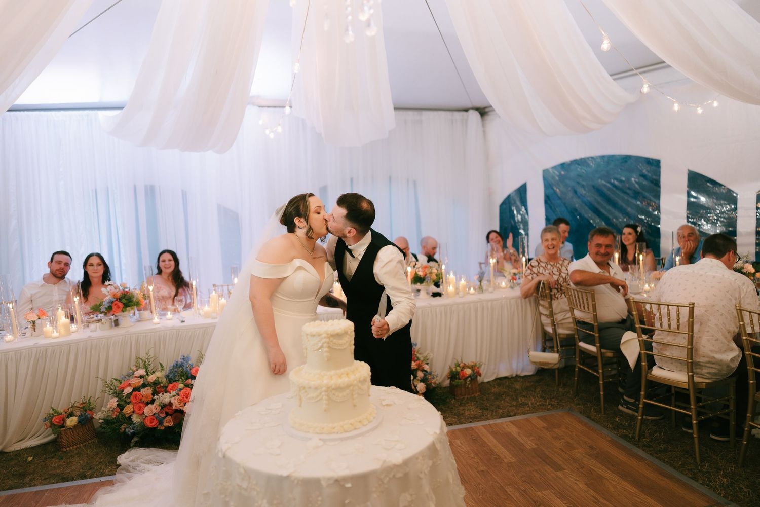 Wedding reception venue features flowing white fabric drapes and elegant table settings.