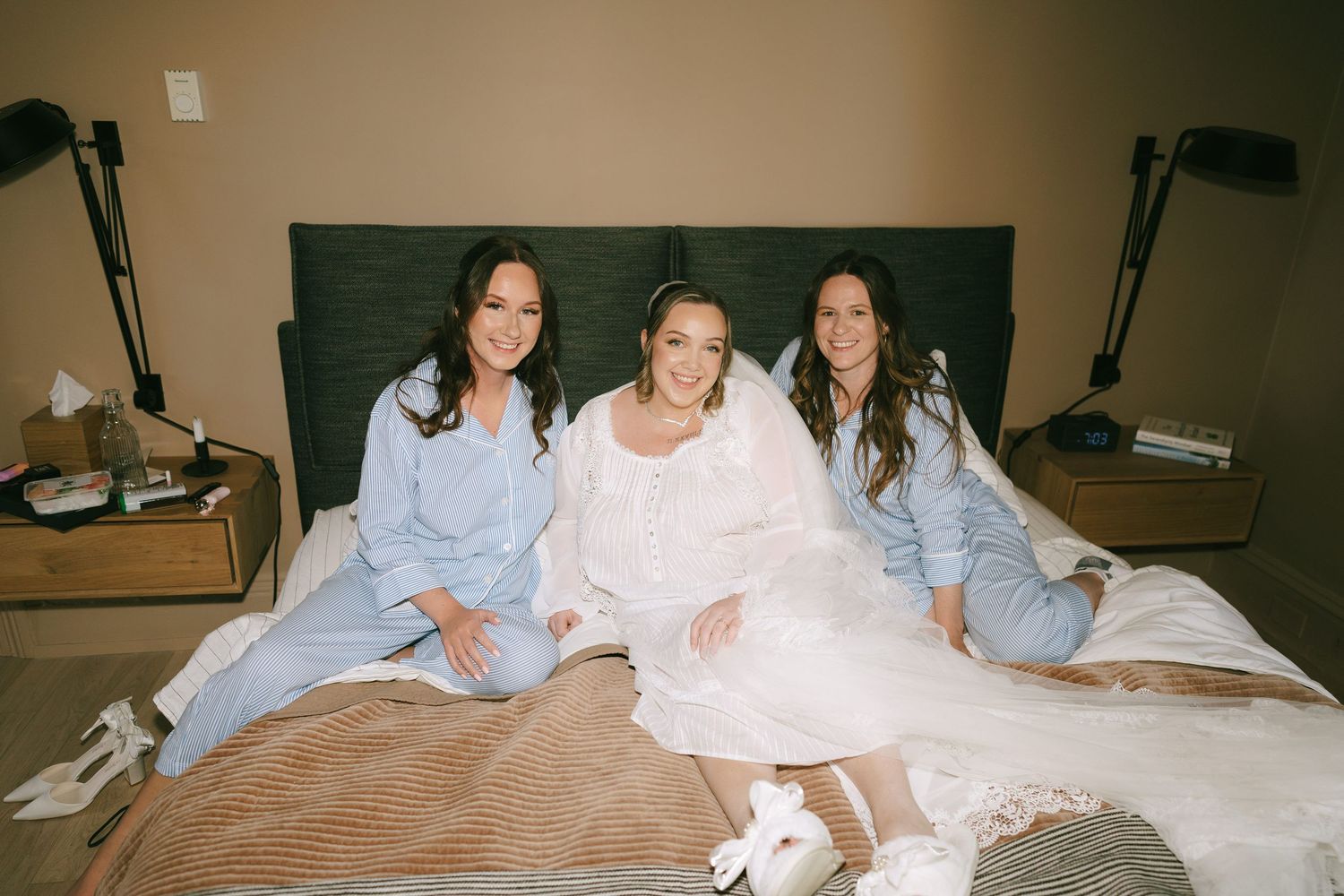 People in casual attire relaxing together on a comfortable bed in warm lighting.