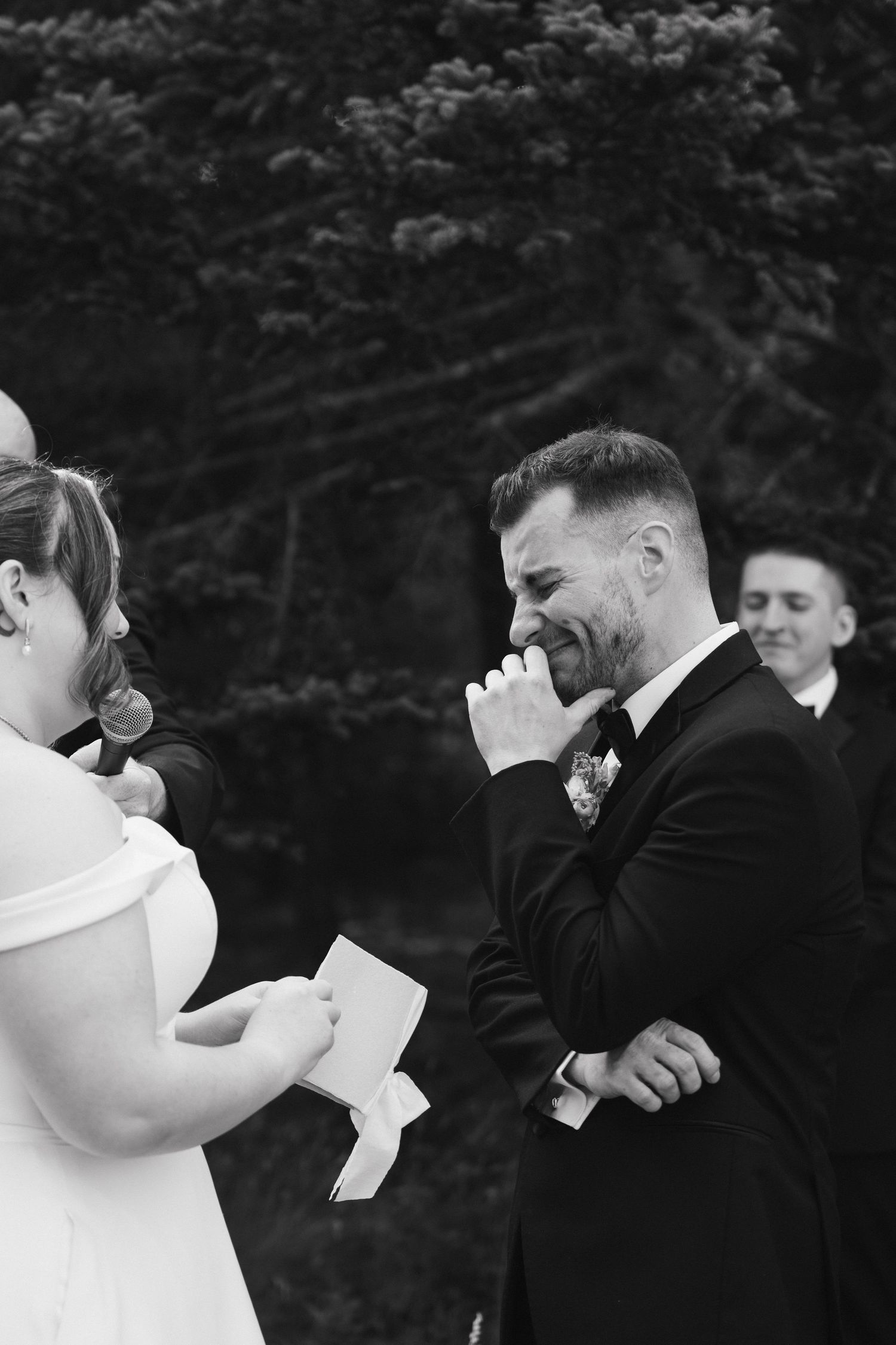 Black and white emotional reactions during wedding vow reading ceremony.