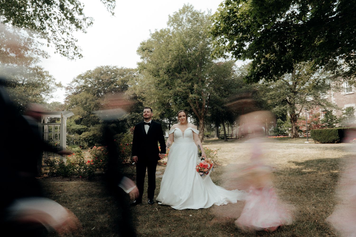 Wedding couple poses outdoors beneath autumn trees in a romantic garden setting.