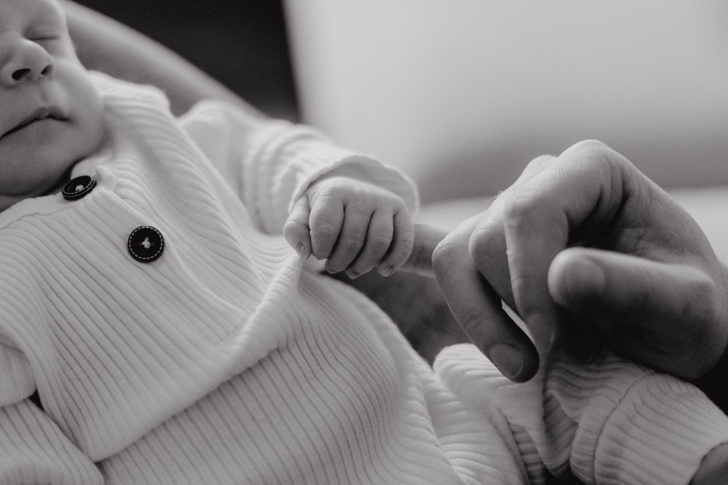 A peaceful newborn resting on soft gray fabric in black and white.